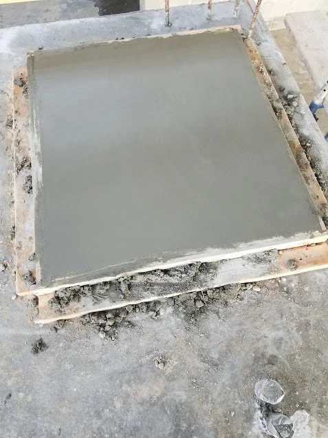 Freshly poured concrete in a square mold on a construction site.