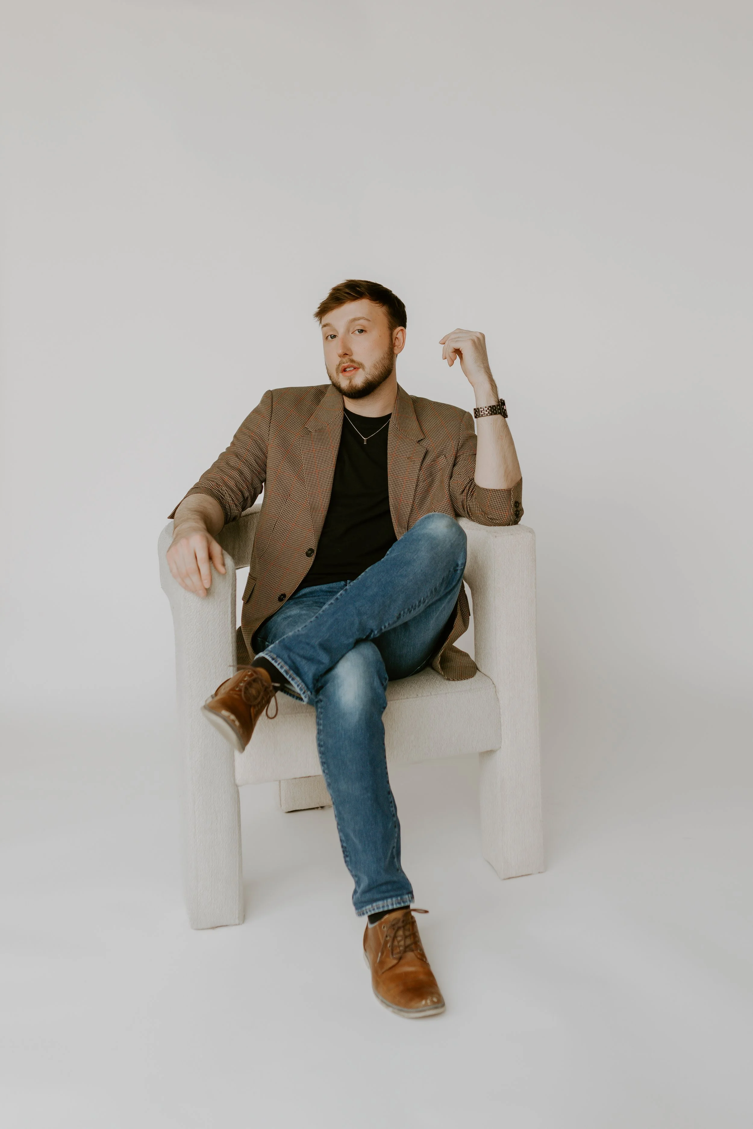William Randall seated casually in a chair during a studio photoshoot.