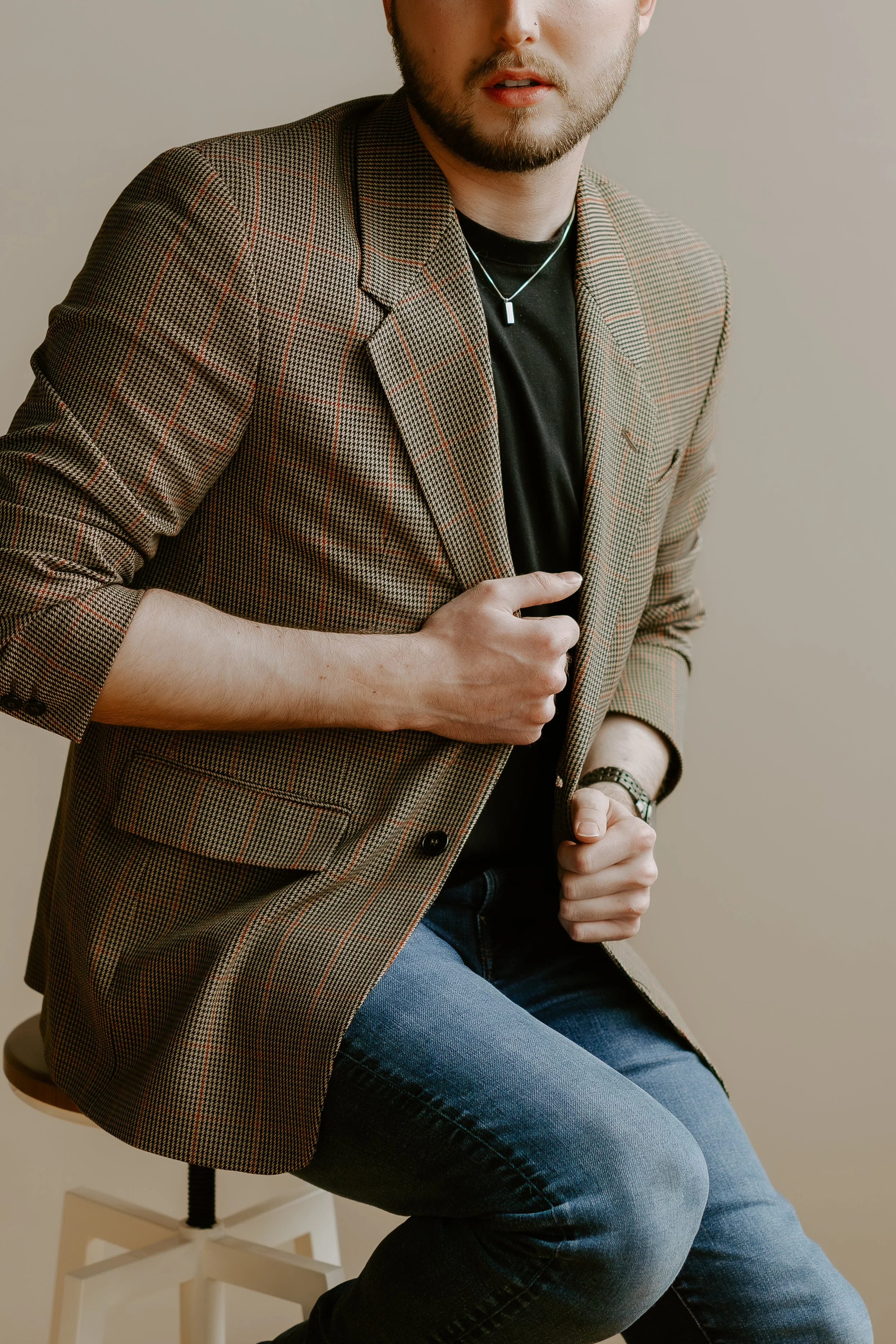 Close-up of William Randall adjusting his blazer in a studio setting.