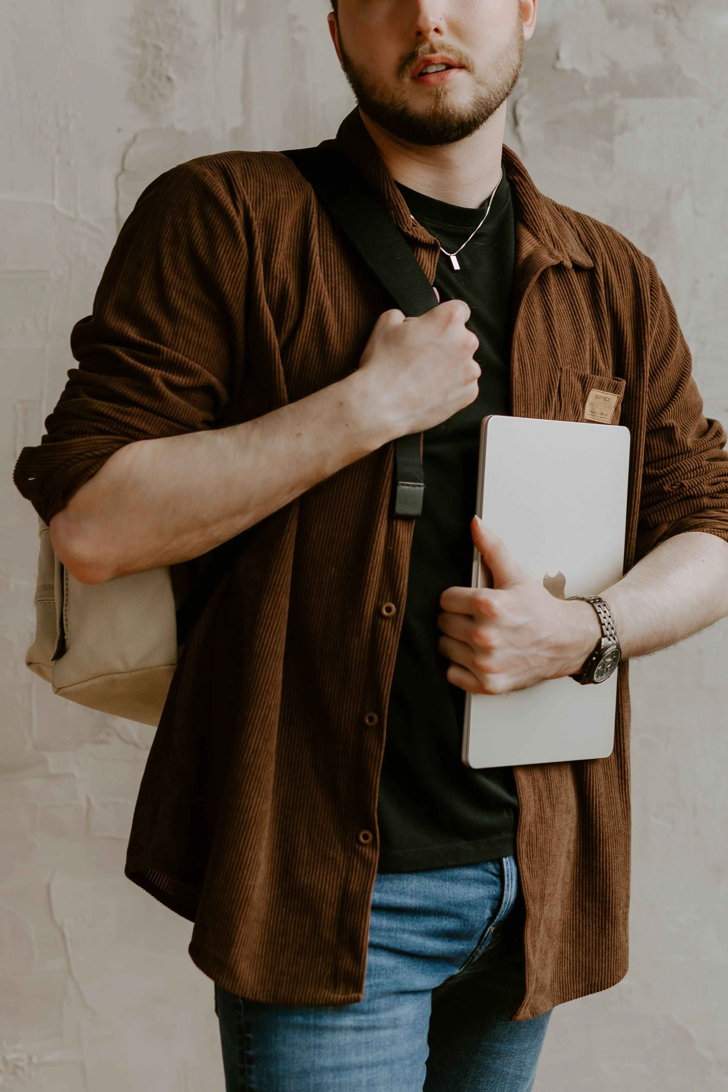 William Randall holding a laptop and camera bag for content creation work.