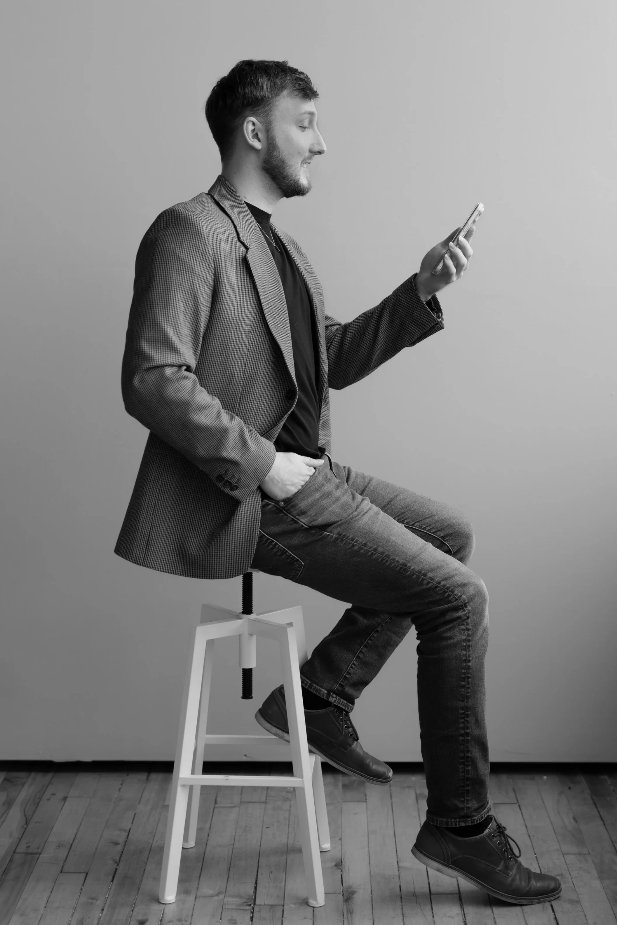 William Randall looking at a smartphone in a side-profile black and white portrait.
