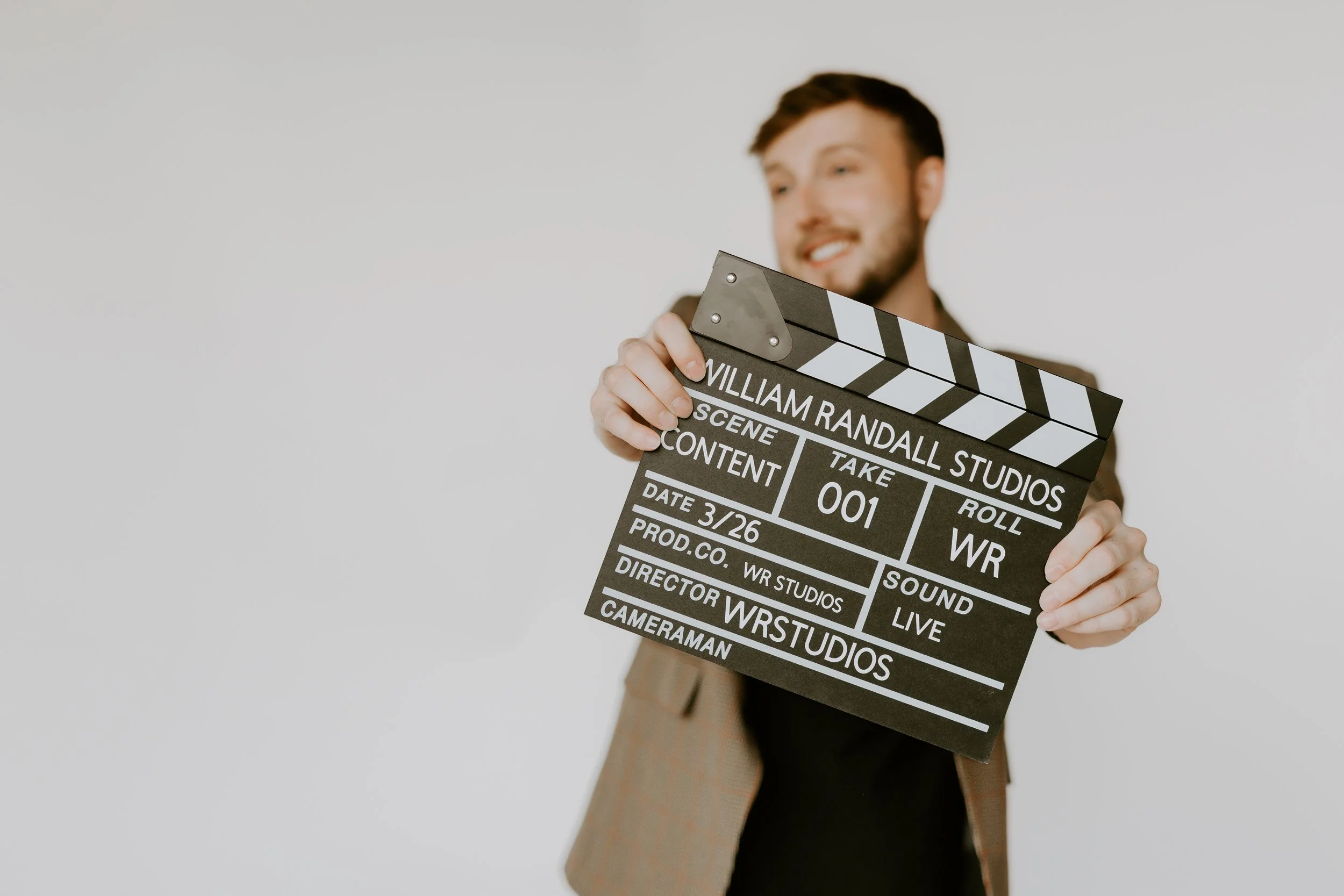 William Randall holding a clapperboard during a content shoot with text overlay “Built for results.”