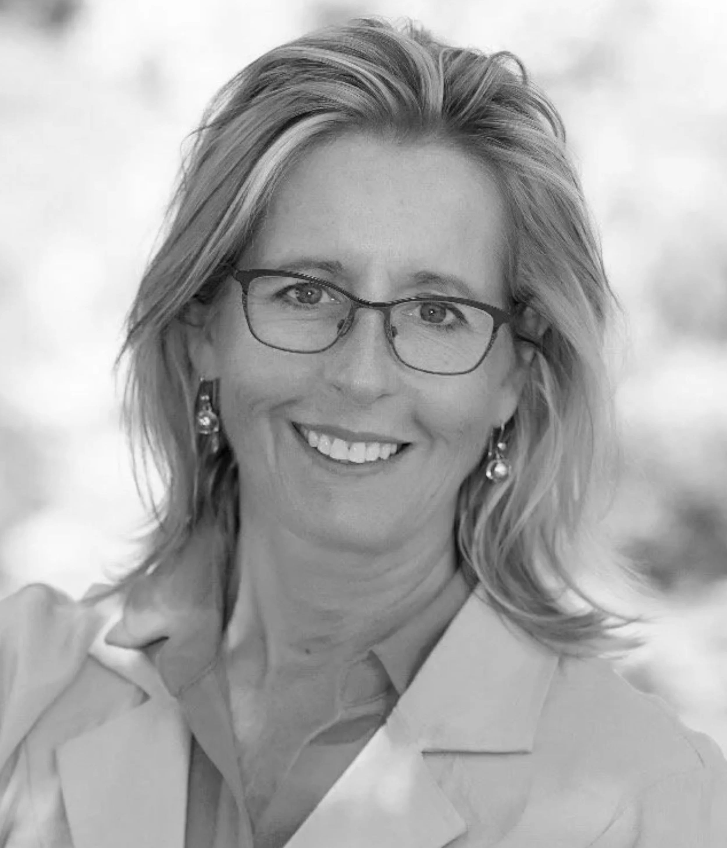 Woman smiling with glasses and earrings.