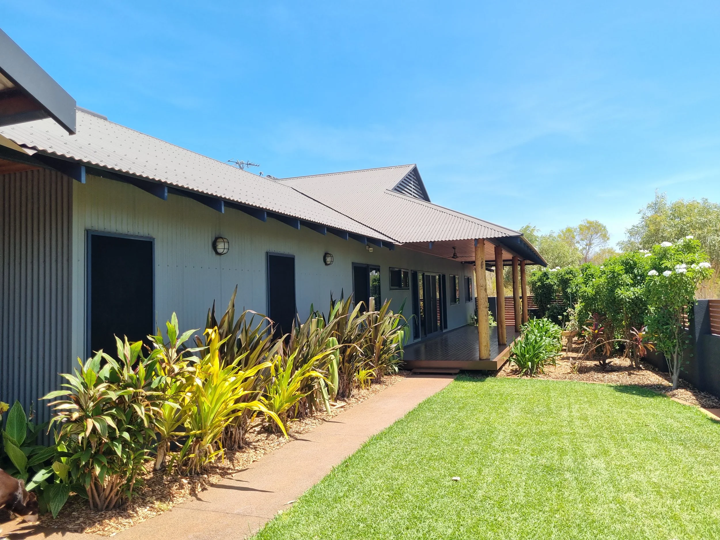 Pre-purchase building inspection of a Broome-style home with corrugated cladding, timber pole veranda and tropical gardens