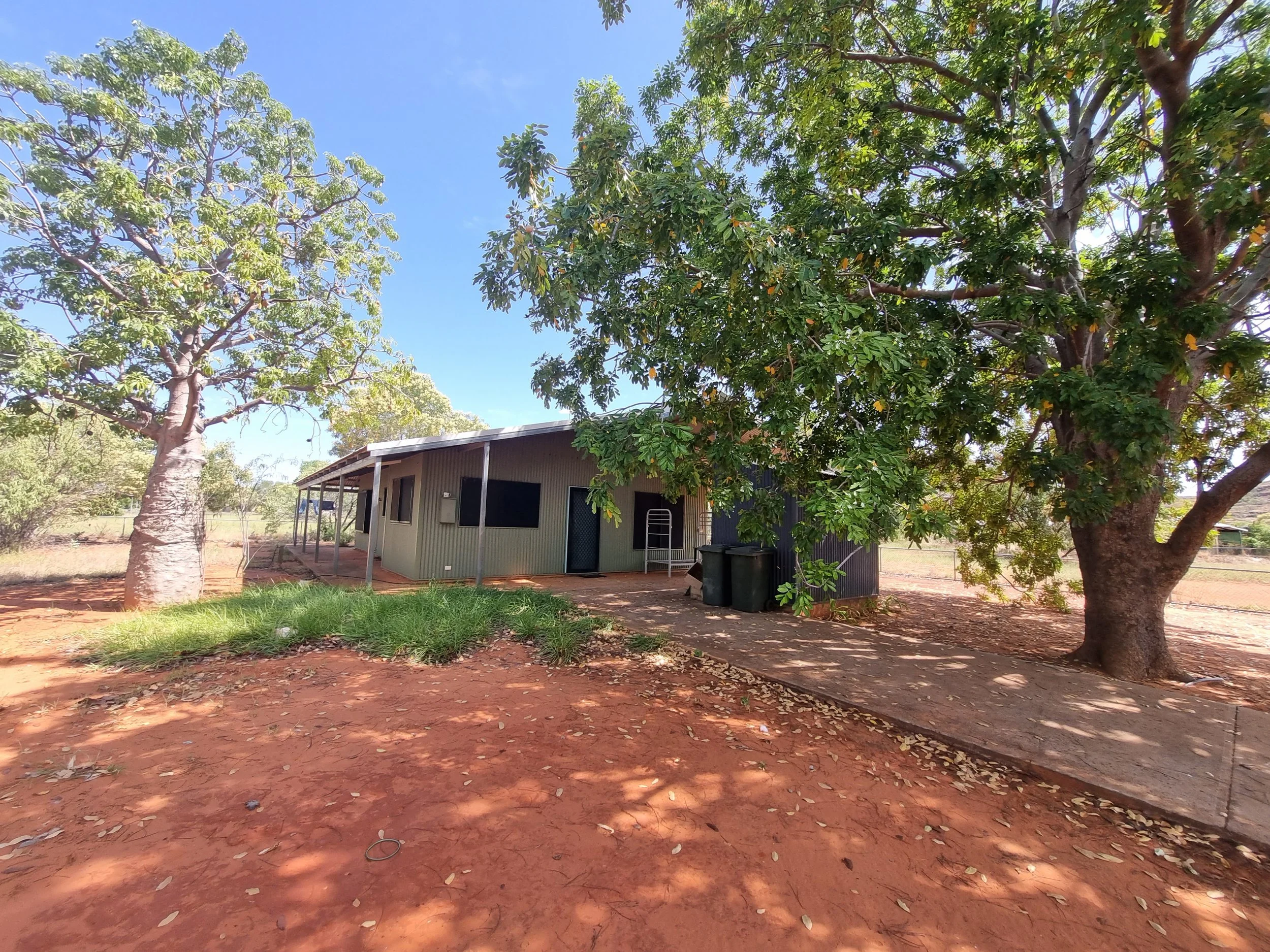 Corrugated steel home in a remote Kimberley community with boab tree and red pindan soil, inspected by Cooee Constructions