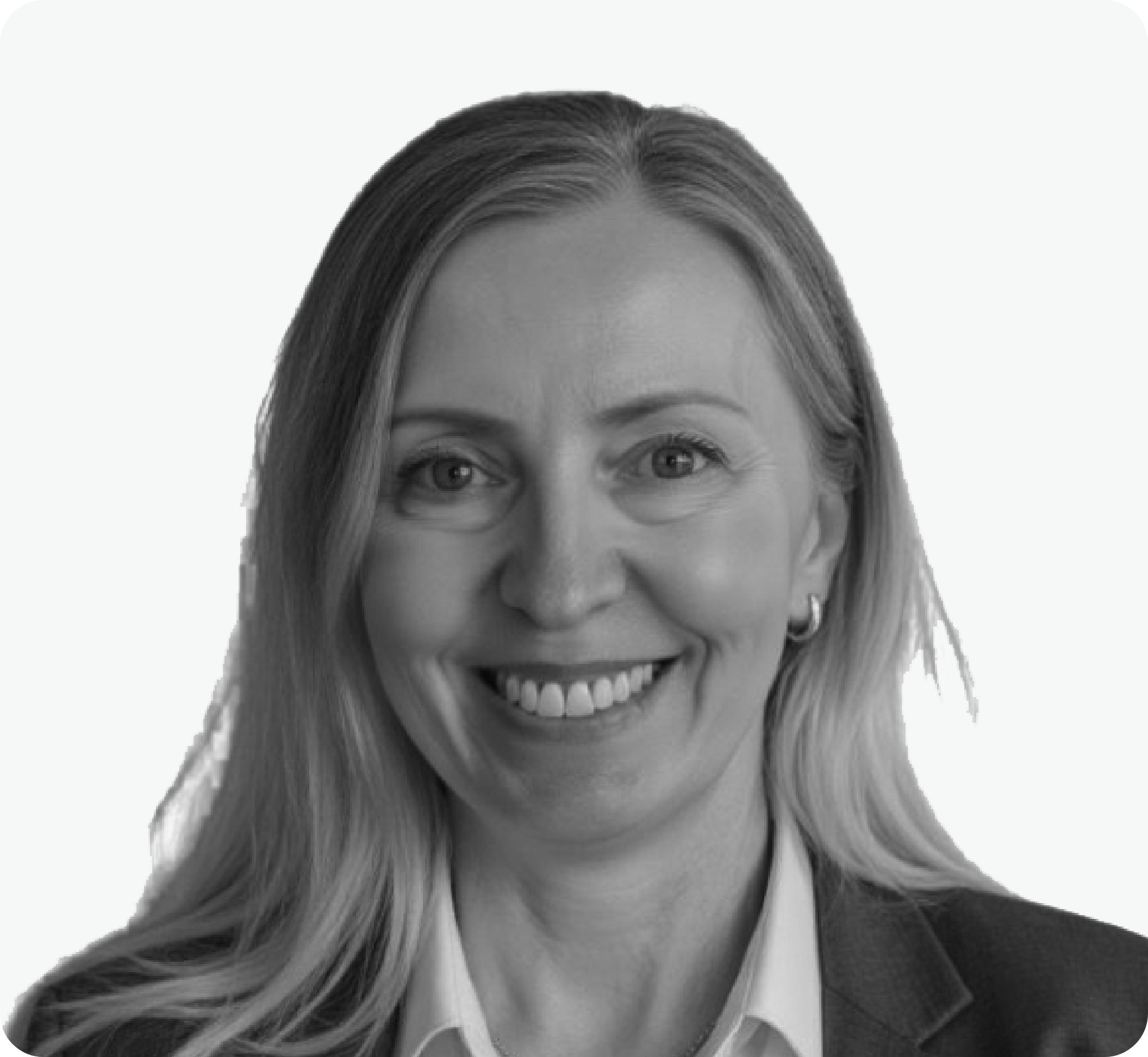 Black and white headshot of a smiling woman with long, wavy hair, wearing a blazer and earrings.