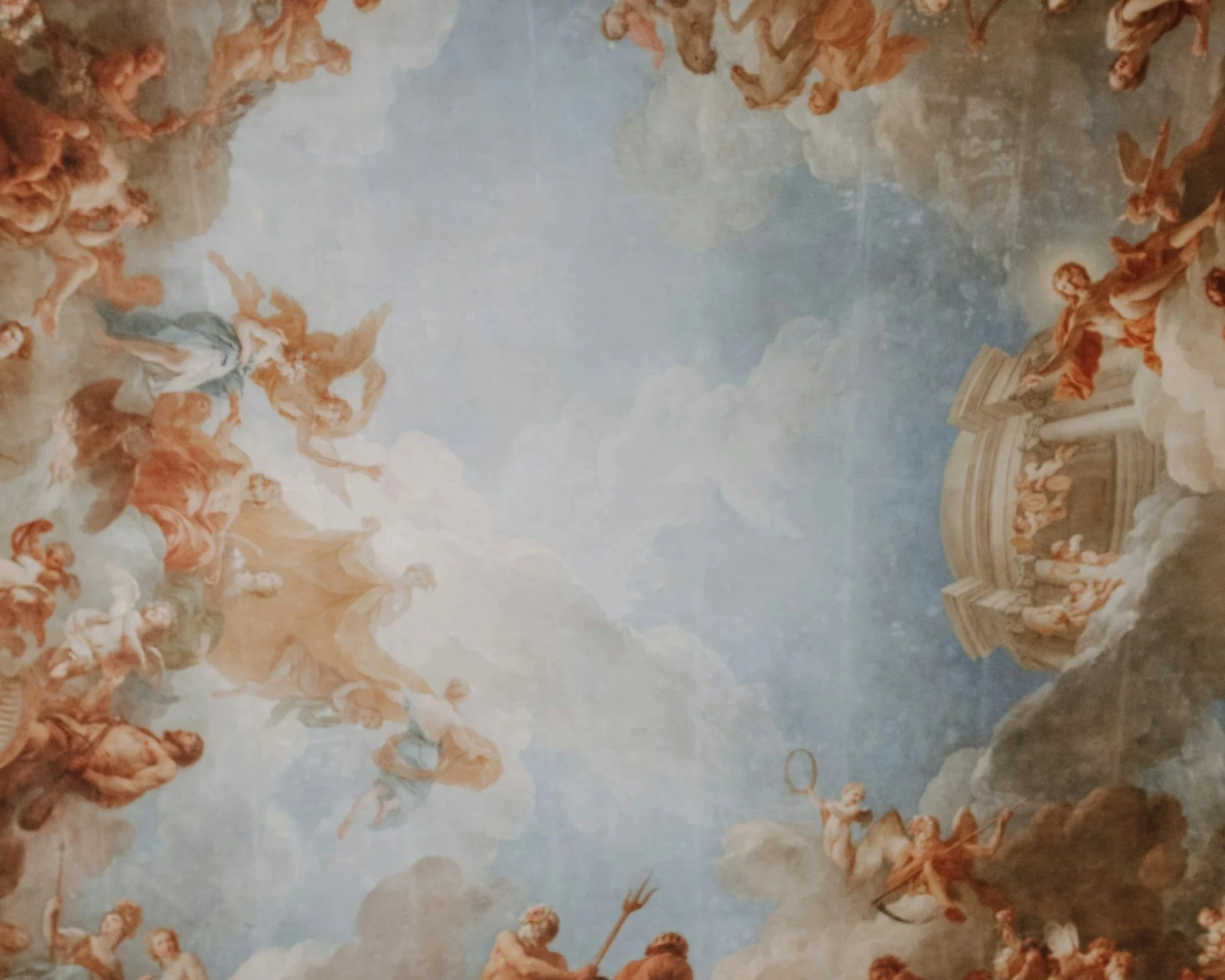 A Baroque-style ceiling fresco with mythological figures, angels, and clouds, featuring a central draped structure with cherubs and flying figures.