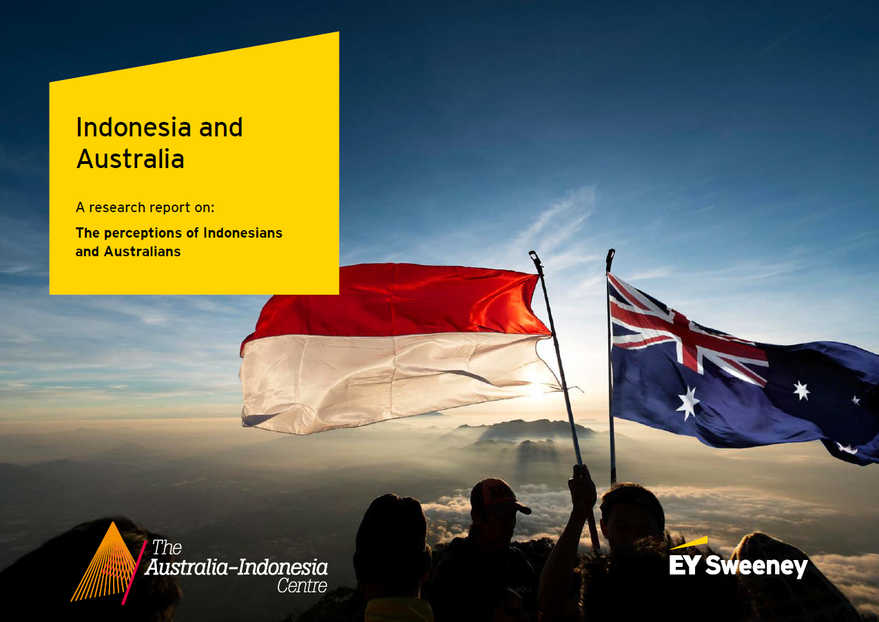 People holding Indonesian and Australian flags against a sunset or sunrise sky with clouds and mountain silhouette.