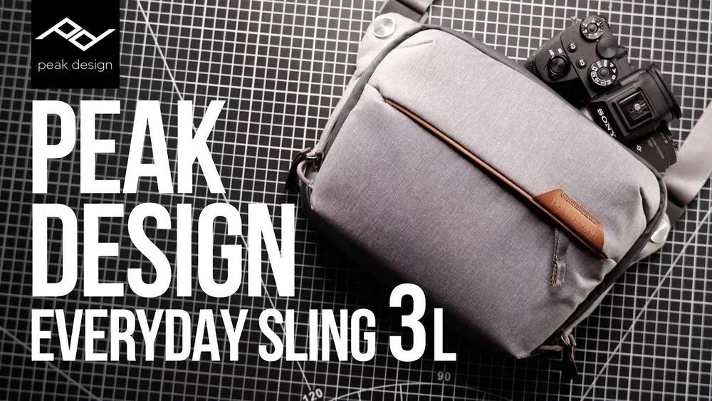 A promotional image for Peak Design showing a gray sling bag with a brown zipper pull, a camera partially inside, and the text "Peak Design, Everyday Sling 3L" on a black and white grid background.