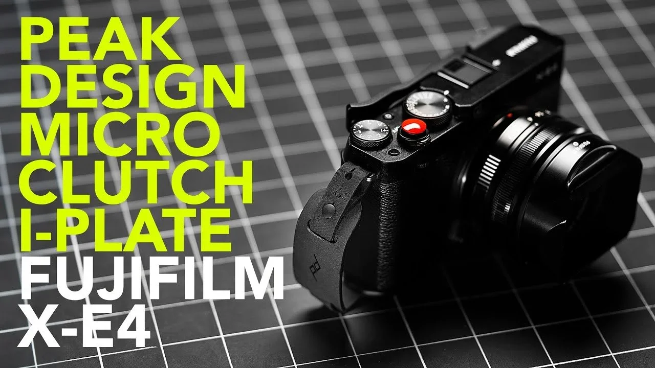 A black Fujifilm X-E4 camera with a lens attached, placed on a black grid cutting mat with white lines. The photo includes large, bold yellow and white text listing camera features and model.