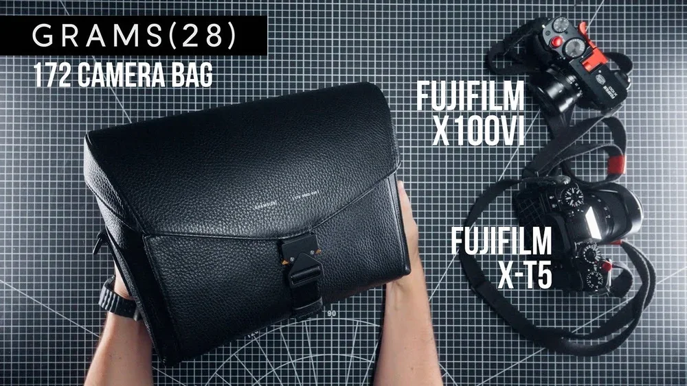 A black camera bag on a grid cutting mat with two Fujifilm cameras labeled X100V and X-T5, and a smaller camera with a strap and red accents. The text indicates the weight of the bag as 28 grams and contains 172 camera pieces or accessories.
