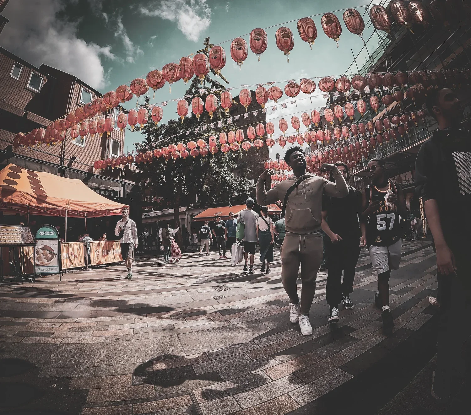 People walking under pink lanterns hanging in Chinese-style street decoration during daytime.