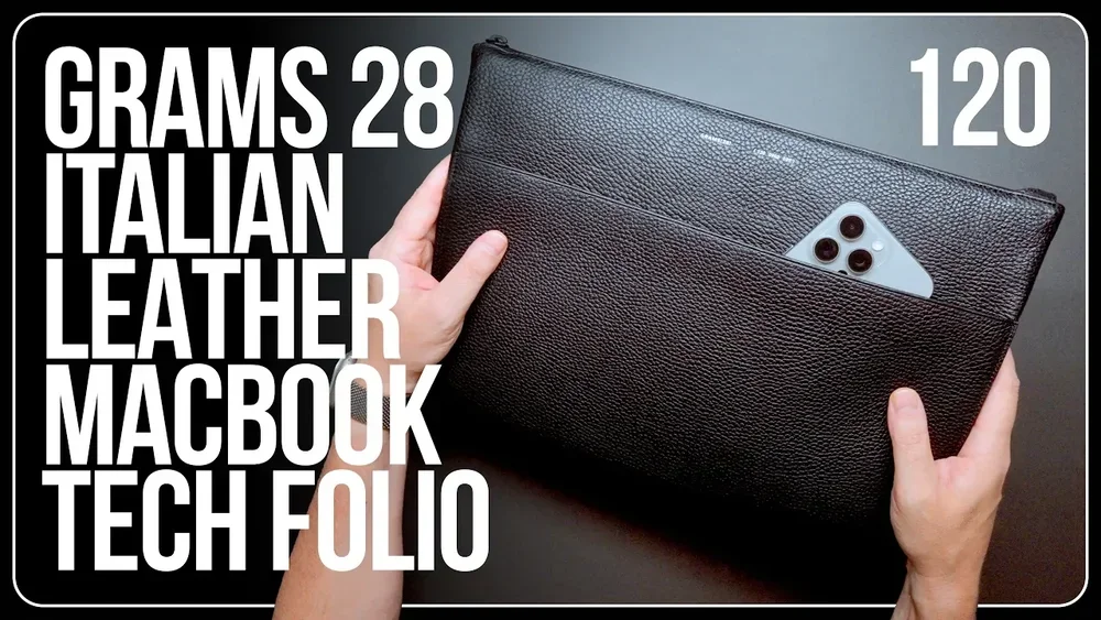 A person holding a black leather tech folio with a smartphone partially visible in a pocket on the front, against a gray background, with large white text overlay listing its specifications.