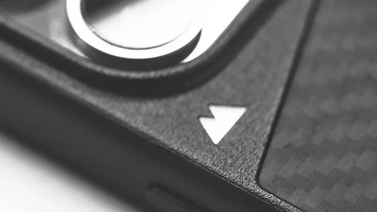 Close-up of a part of a camera or electronic device with a white downward-pointing arrow icon and a textured surface.
