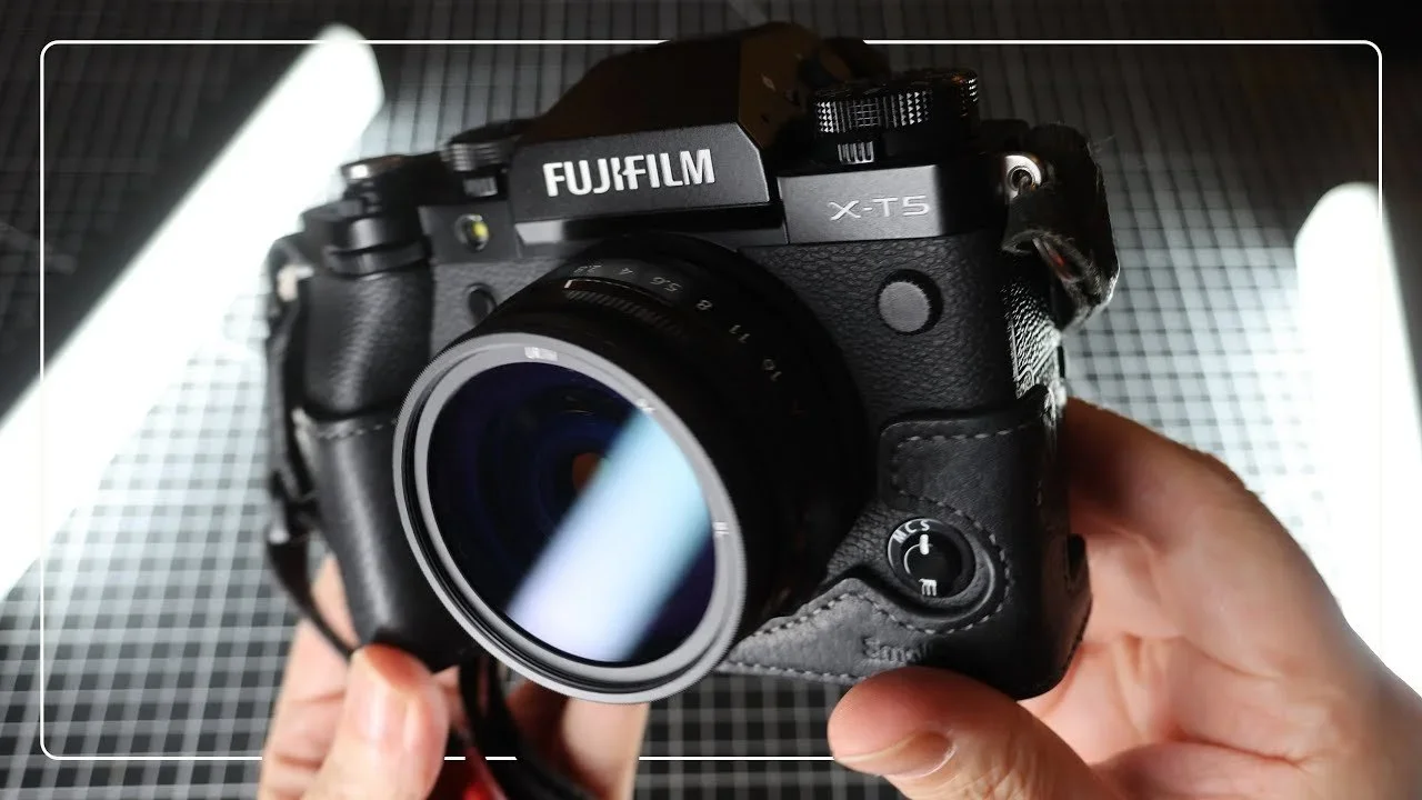 Fujifilm X-T5 mirrorless camera being held in hand, with a focus on the camera body and lens