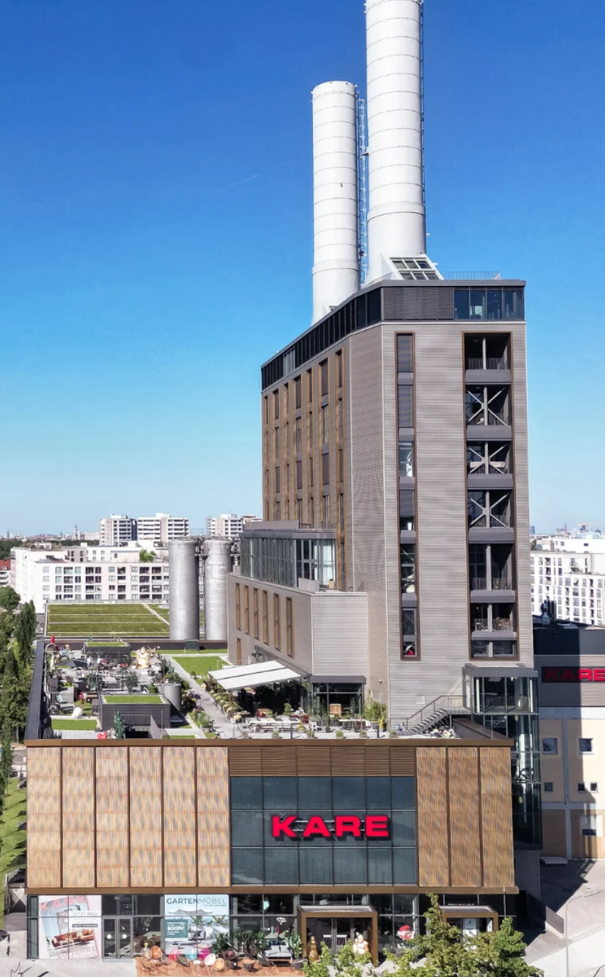 Hochhaus mit KARE-Geschäft im Erdgeschoss, Hochhäuser in der Stadt im Hintergrund, blauer Himmel.