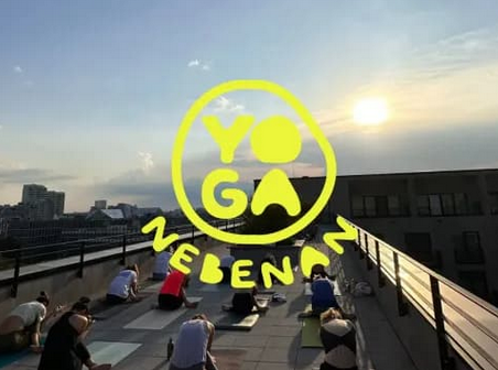 Menschen, die Yoga auf einem Dach bei Sonnenuntergang machen, mit einem gelben Yoga-Logo und dem Text 'Yoga Leben'.