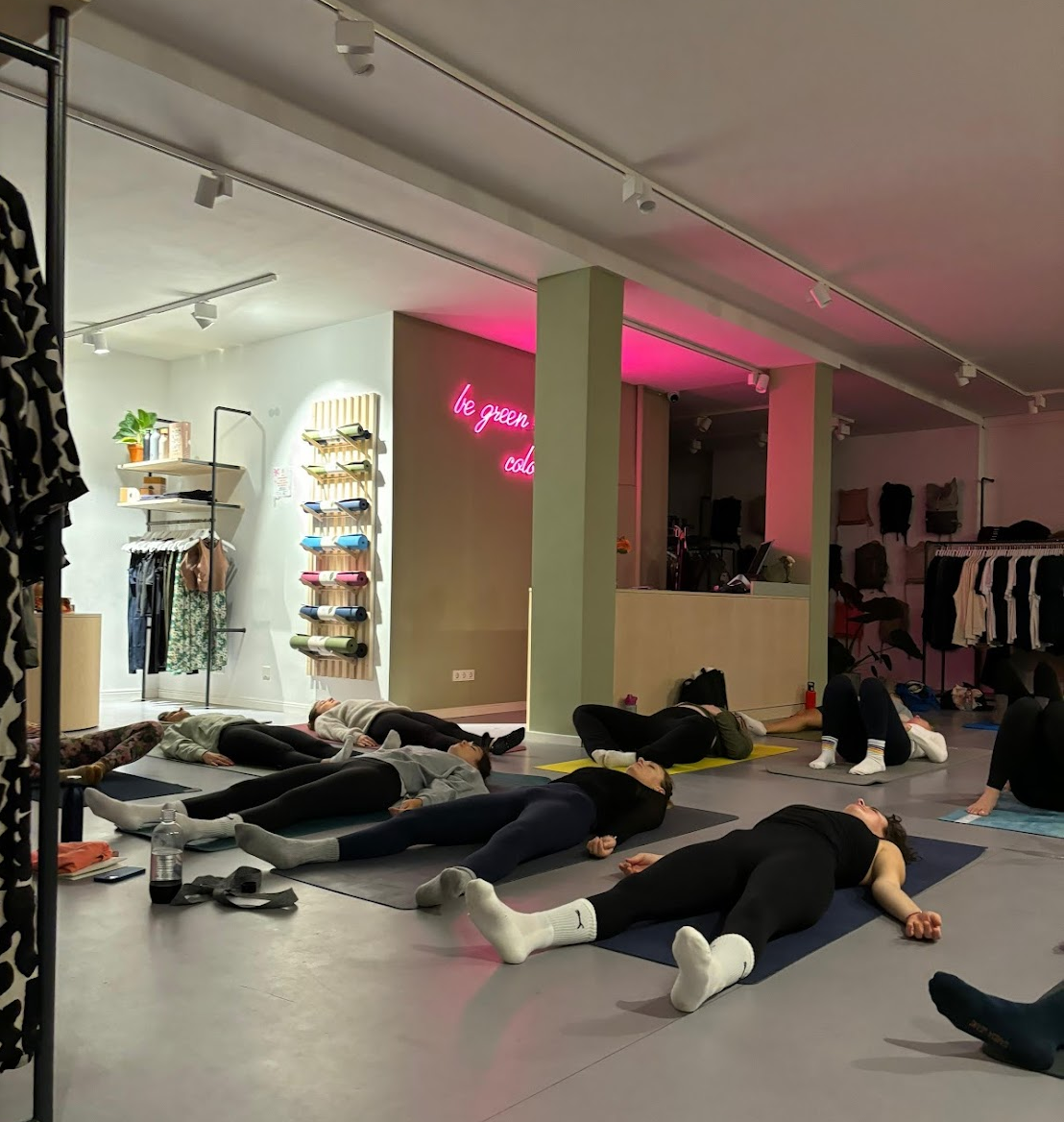 Menschen liegen während einer Yoga-Klasse auf Yogamatten im Raum.