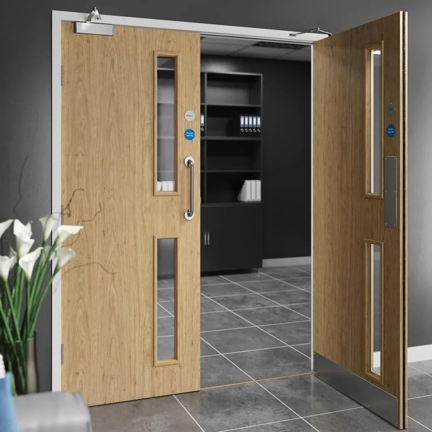 A set of wooden double sliding doors with glass panels opening into a room with dark furniture and shelves, gray tiled flooring, and a gray wall.
