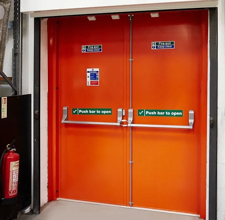 Orange fire exit double doors with push bars and safety signs on top.