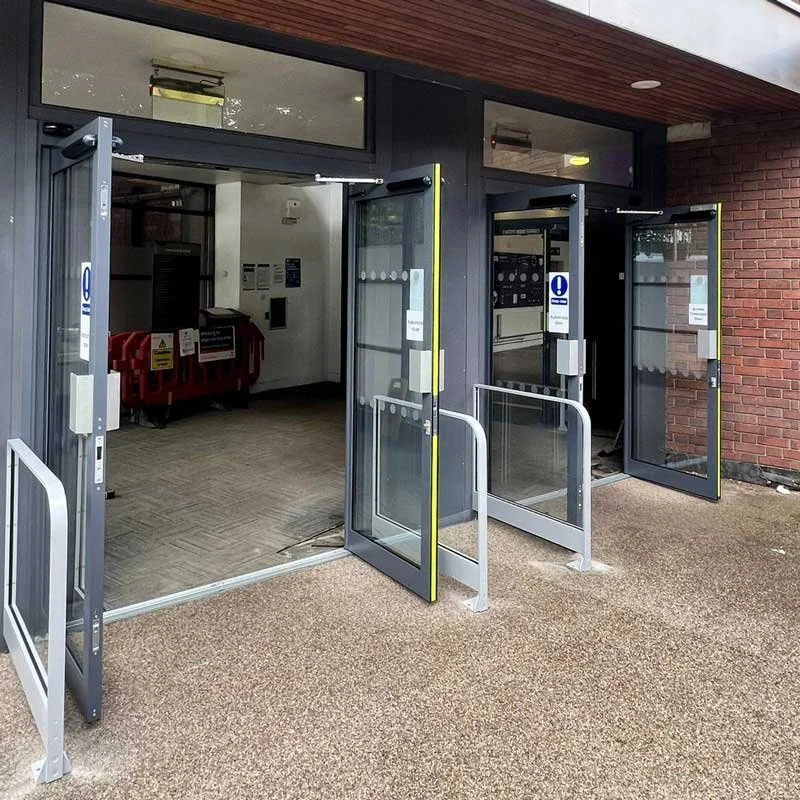 Open safety doors at the entrance of a building, revealing an interior with mailboxes and utility panels.