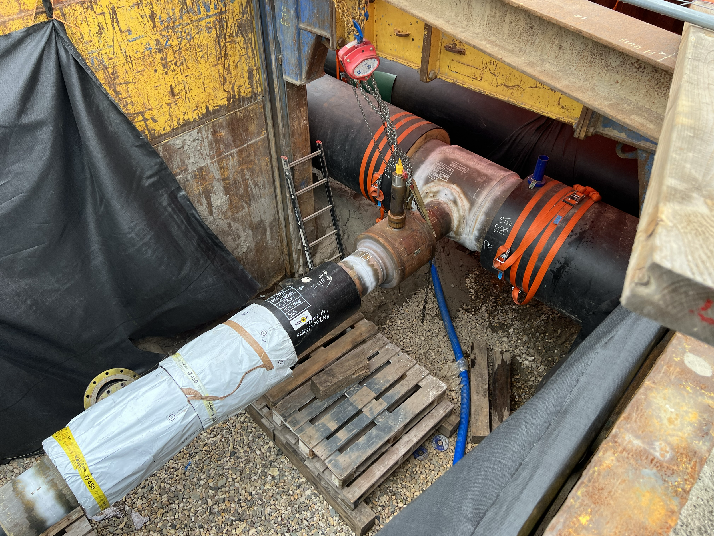 Ondergrondse infrastructuur met verbonden buizen en een ladder, onderdeel van een technische constructie of installatie.