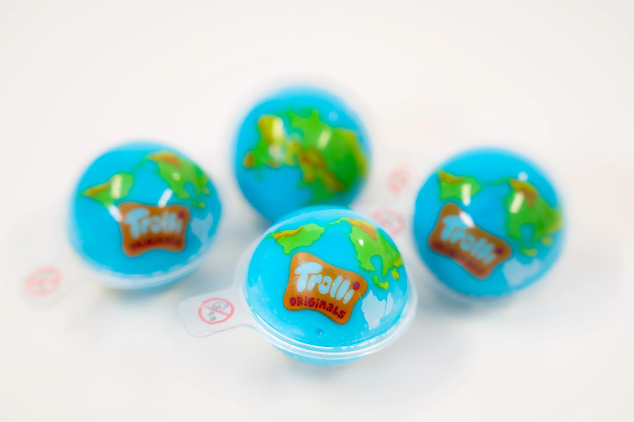 Four blue Truffly Originals candies with globe designs on a white surface.
