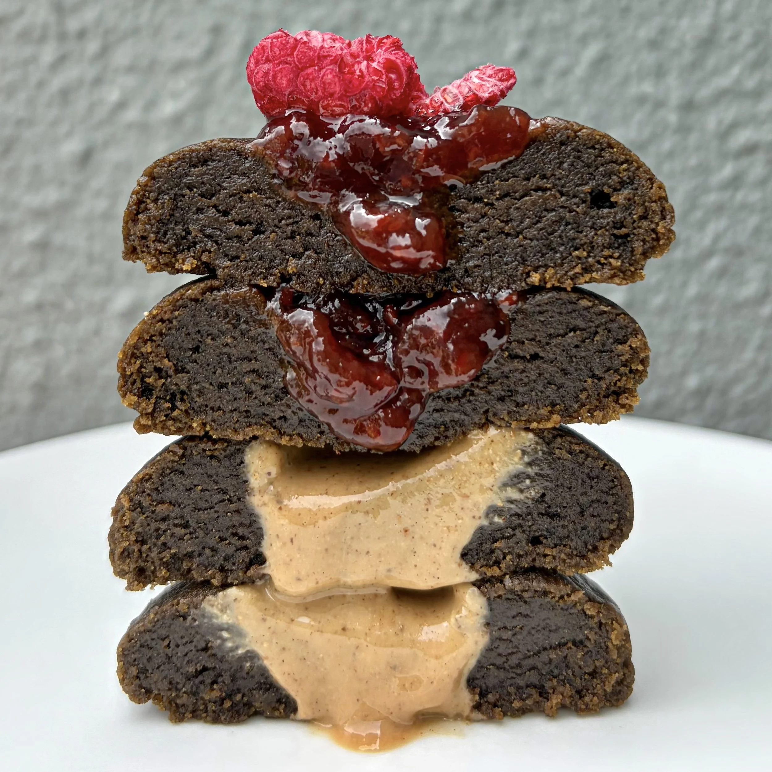 Stacked hojicha cookies with raspberry filling and hazelnut made with dark roasted hojicha from a Singapore matcha bakery.