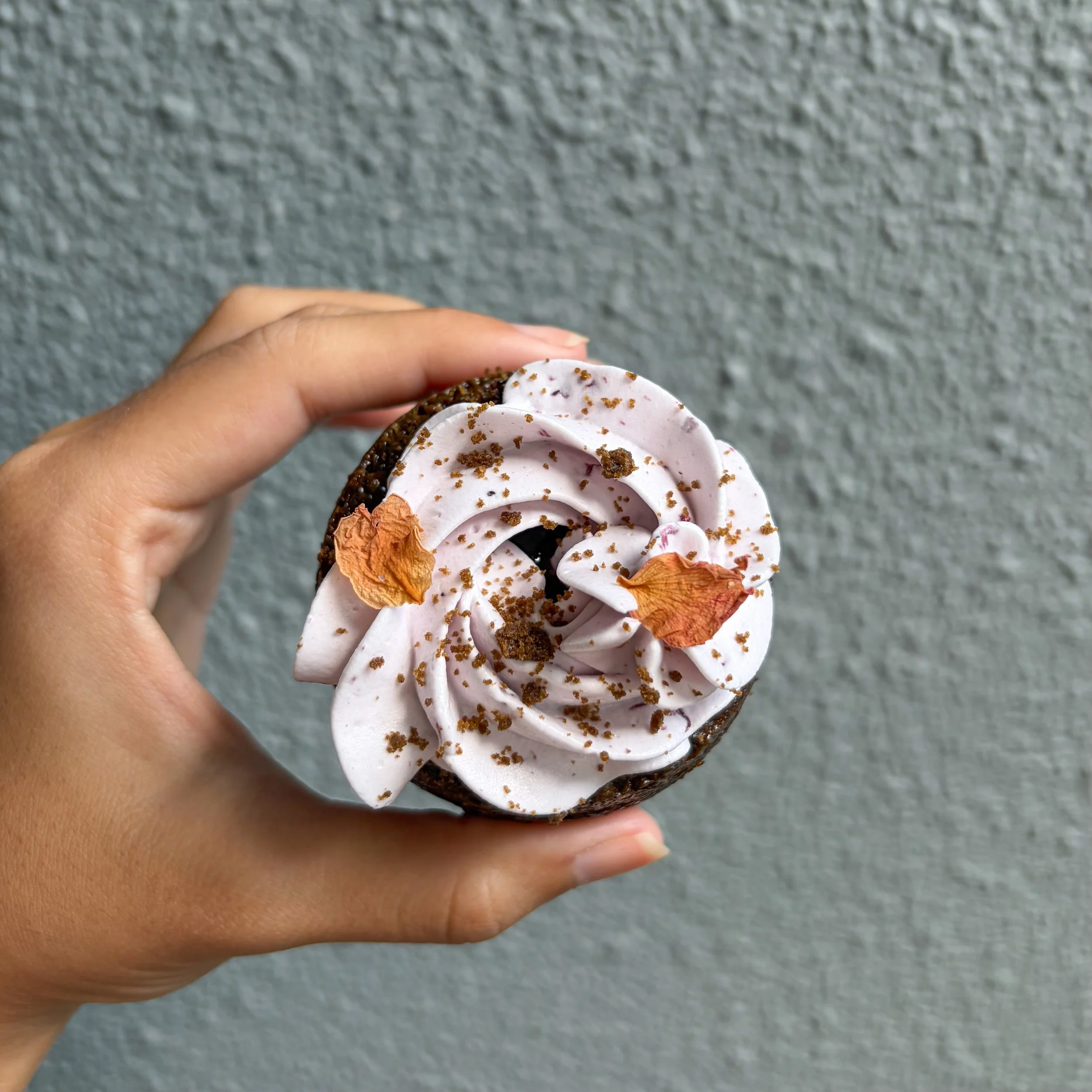 Hand holding a hojicha gateau cake topped with cream made with dark roasted hojicha from a Singapore matcha dessert bakery