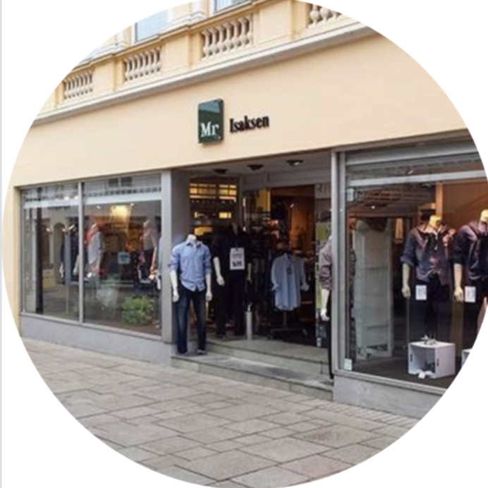 Clothing store named Mr. Isaksen with mannequins dressed in casual and formal attire displayed outside and inside the storefront.