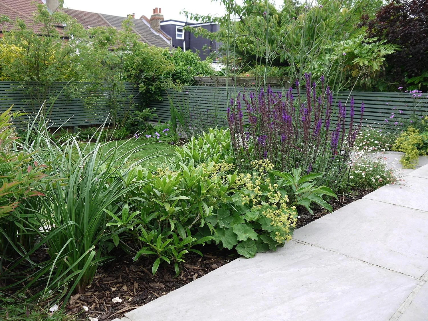 Garten mit bunten Blumen und Sträuchern entlang eines Gehwegs