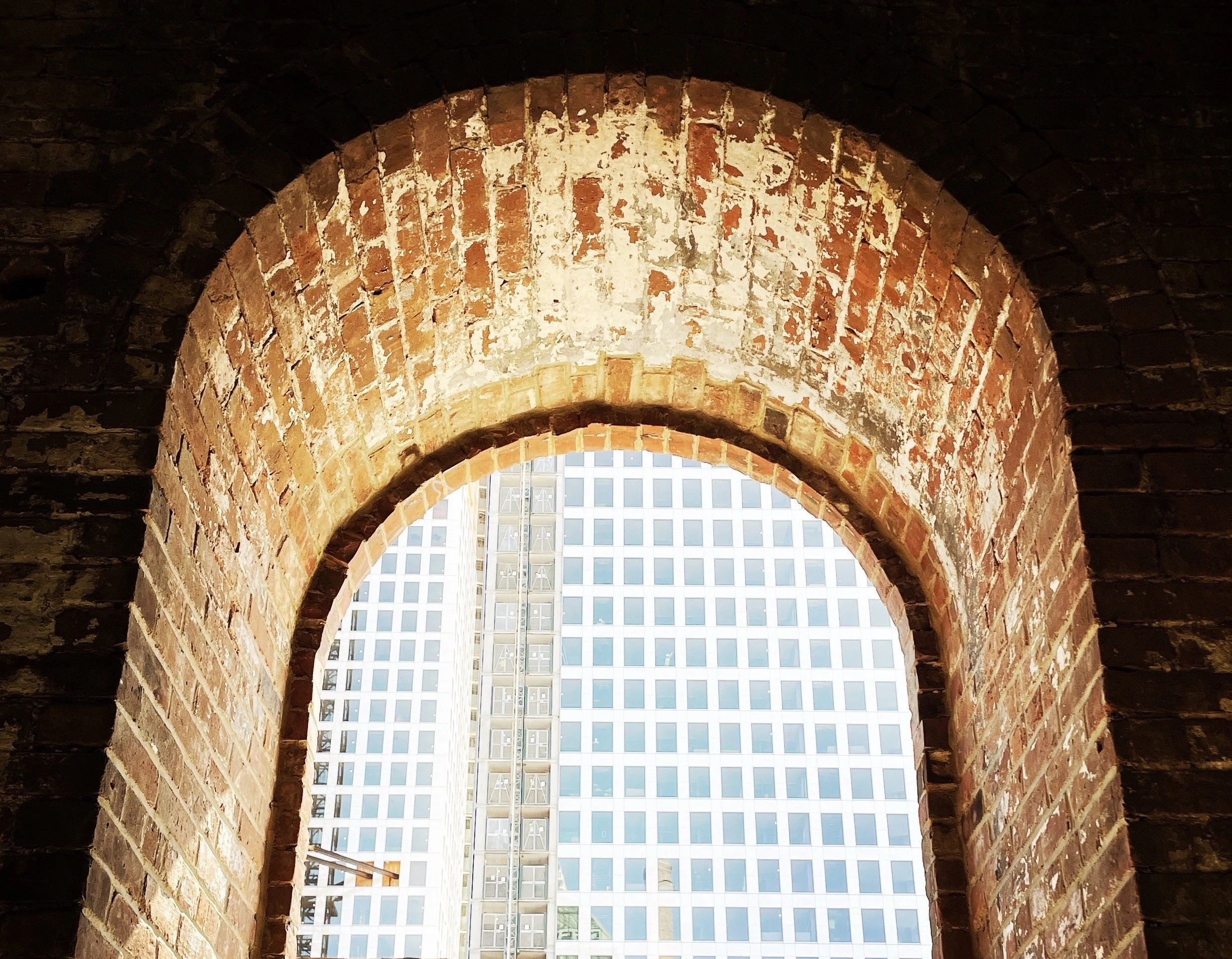 View through a brick archway showing high-rise buildings with glass windows