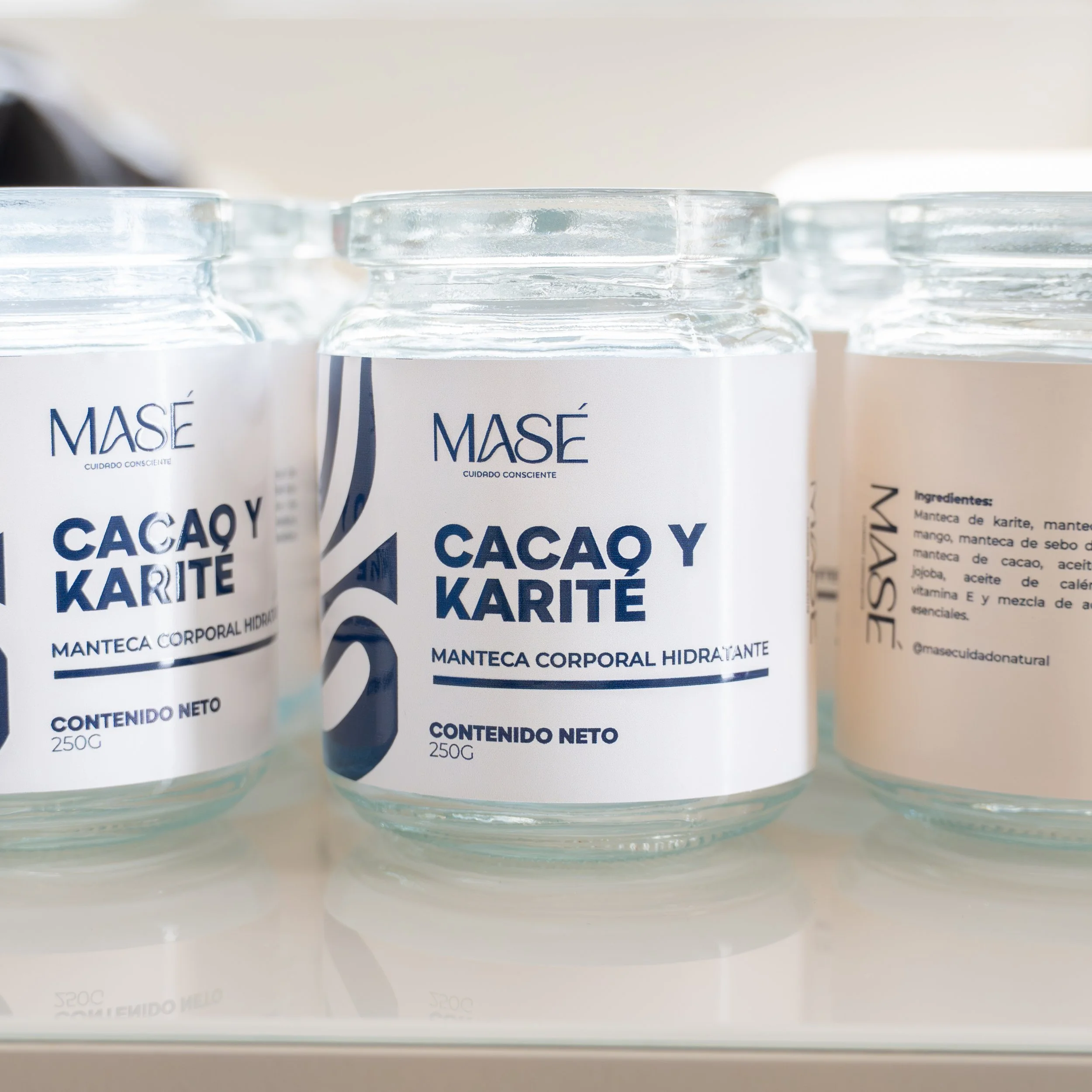 Frascos de crema corporal hidratante con etiqueta que dice 'Cacao y Karité' en español, de la marca Masé.