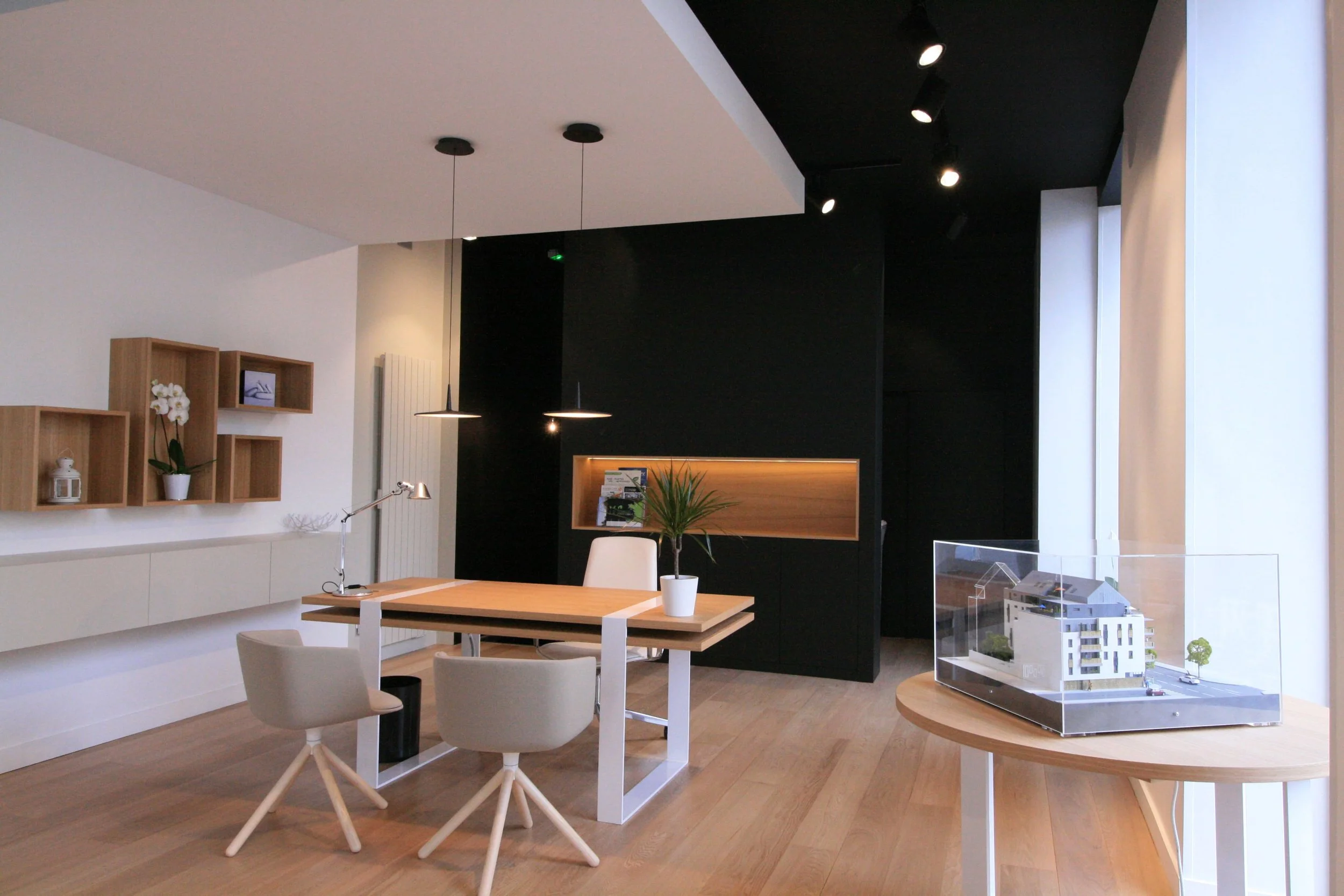 Showroom immobilier La Rochelle, architecture intérieure Niort, aménagement retail Royan, design espace conseil immobilier, mobilier bureau professionnel, cloison noire décorative, parquet chêne clair bureau