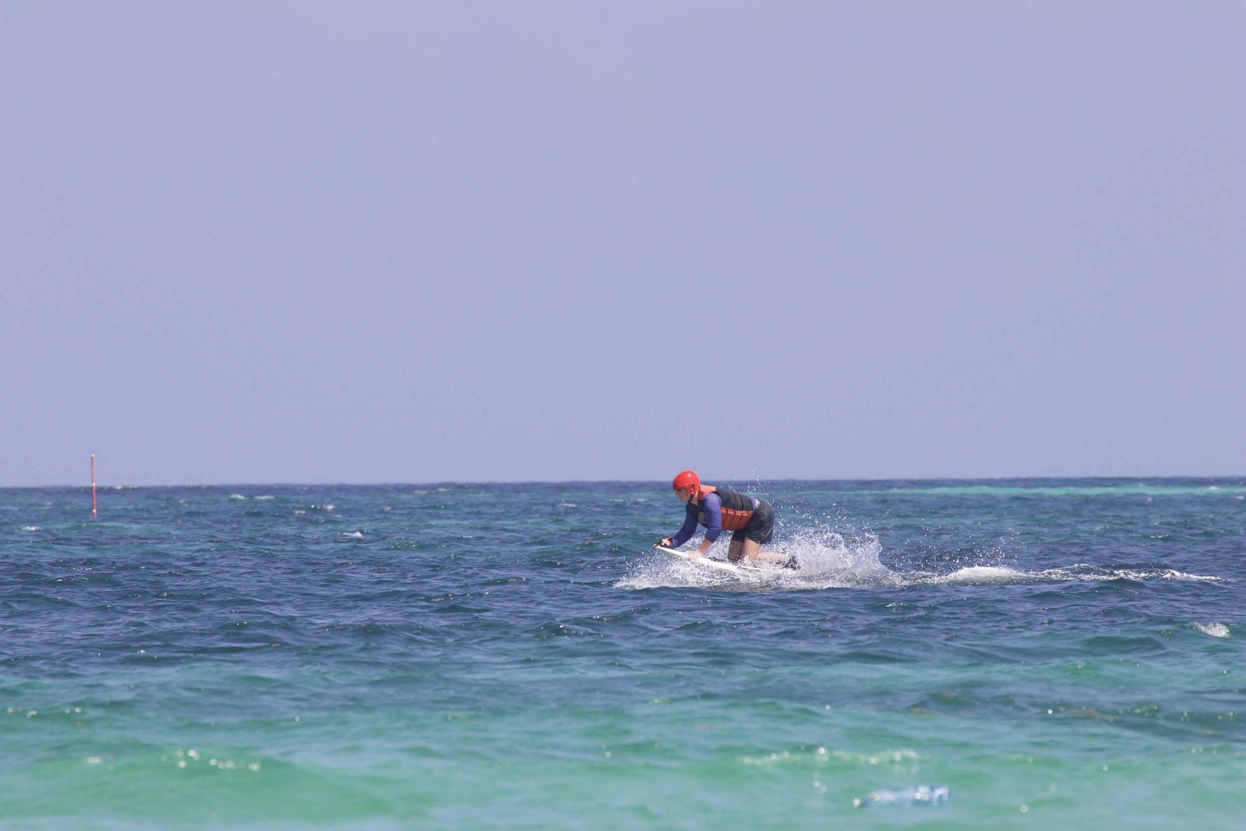 A person wearing a red helmet and a life jacket riding a jet ski on the ocean.