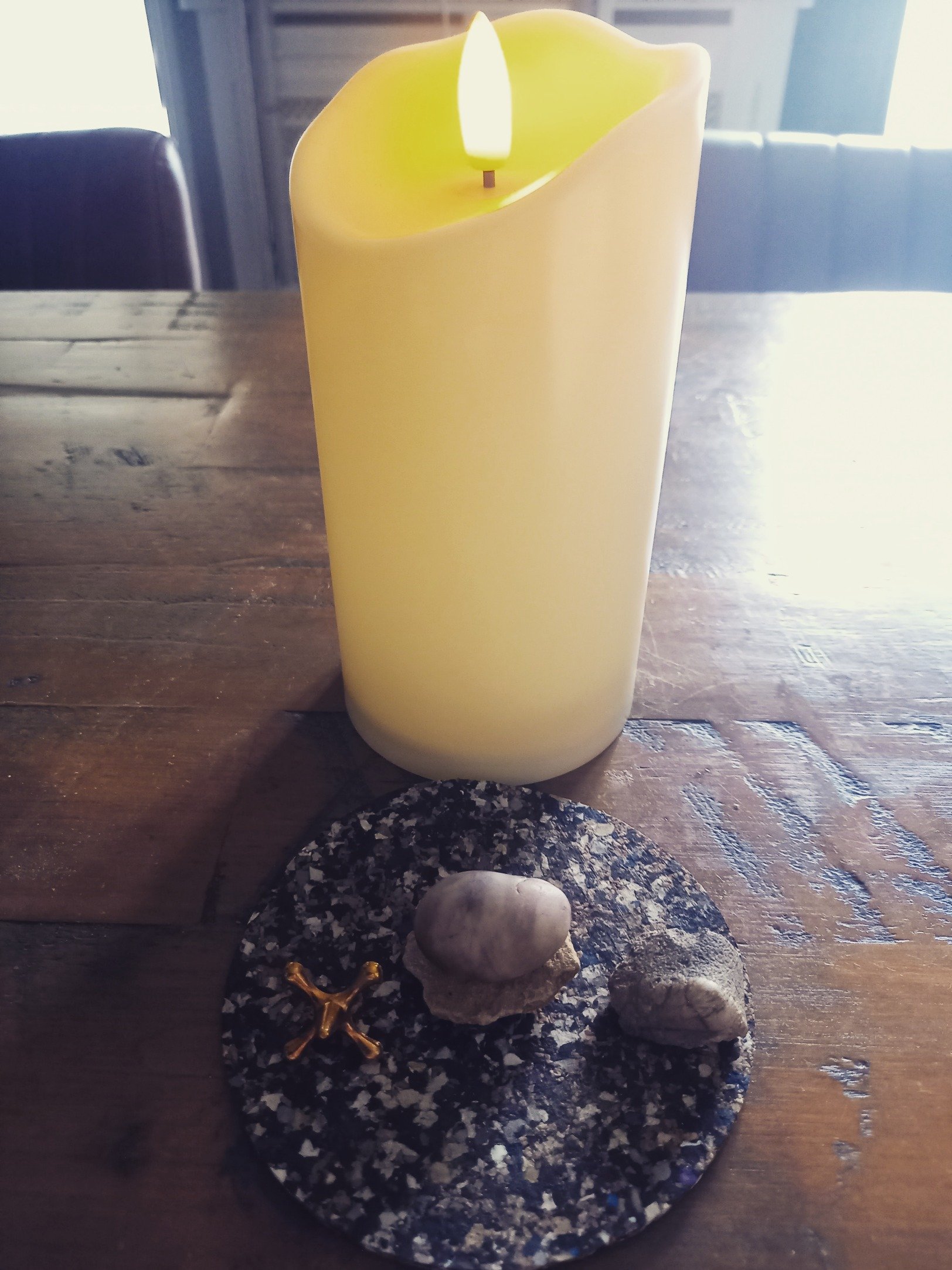 My altar usually sits on a table in my upstairs office. It's been boiling in England for the past week, so I've moved downstairs where it's cooler and set up a little portable altar on a coaster.

As I soon found out, a small tealight adds a surprisi
