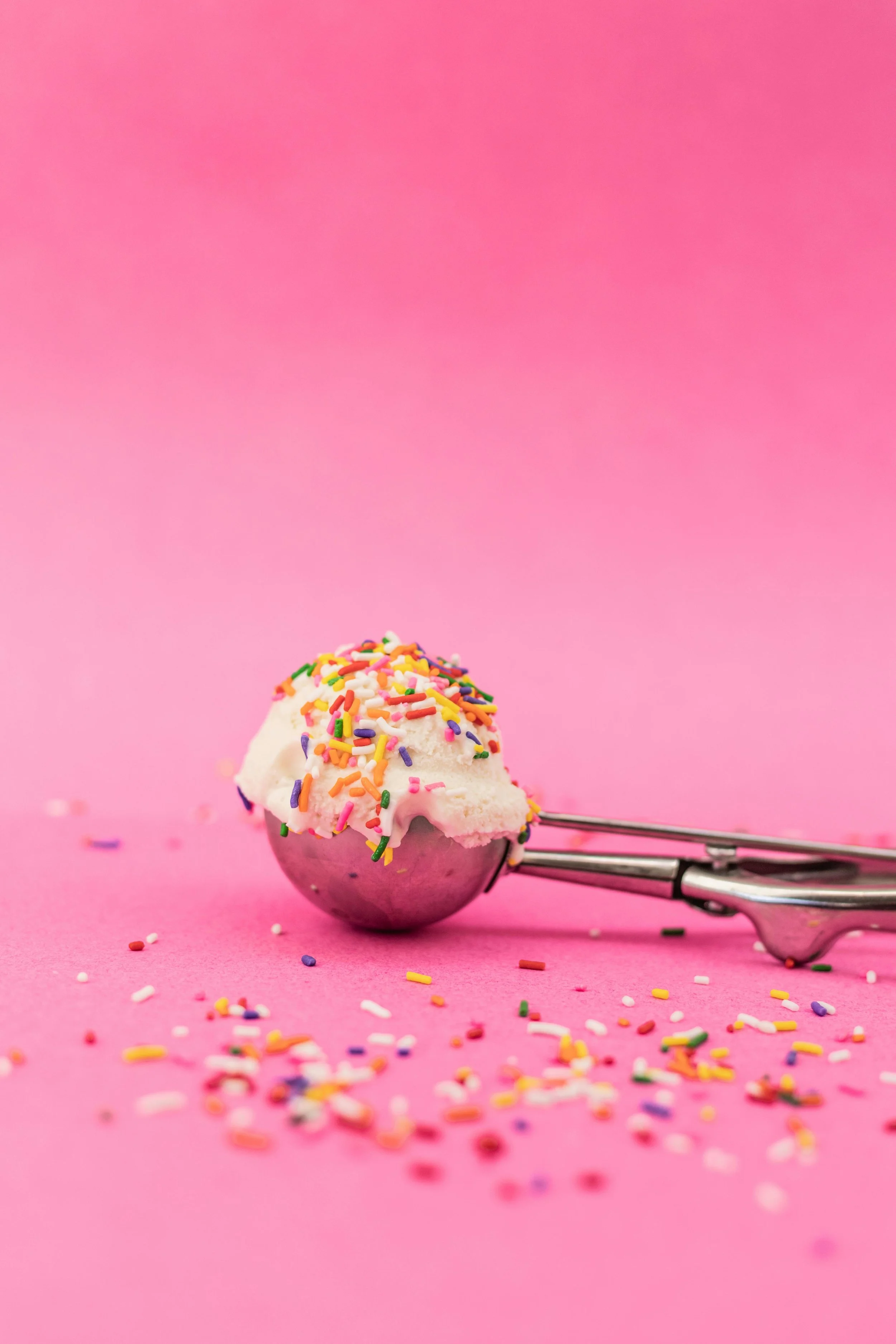 Ice cream scoop with colourful sprinkles on a pink background