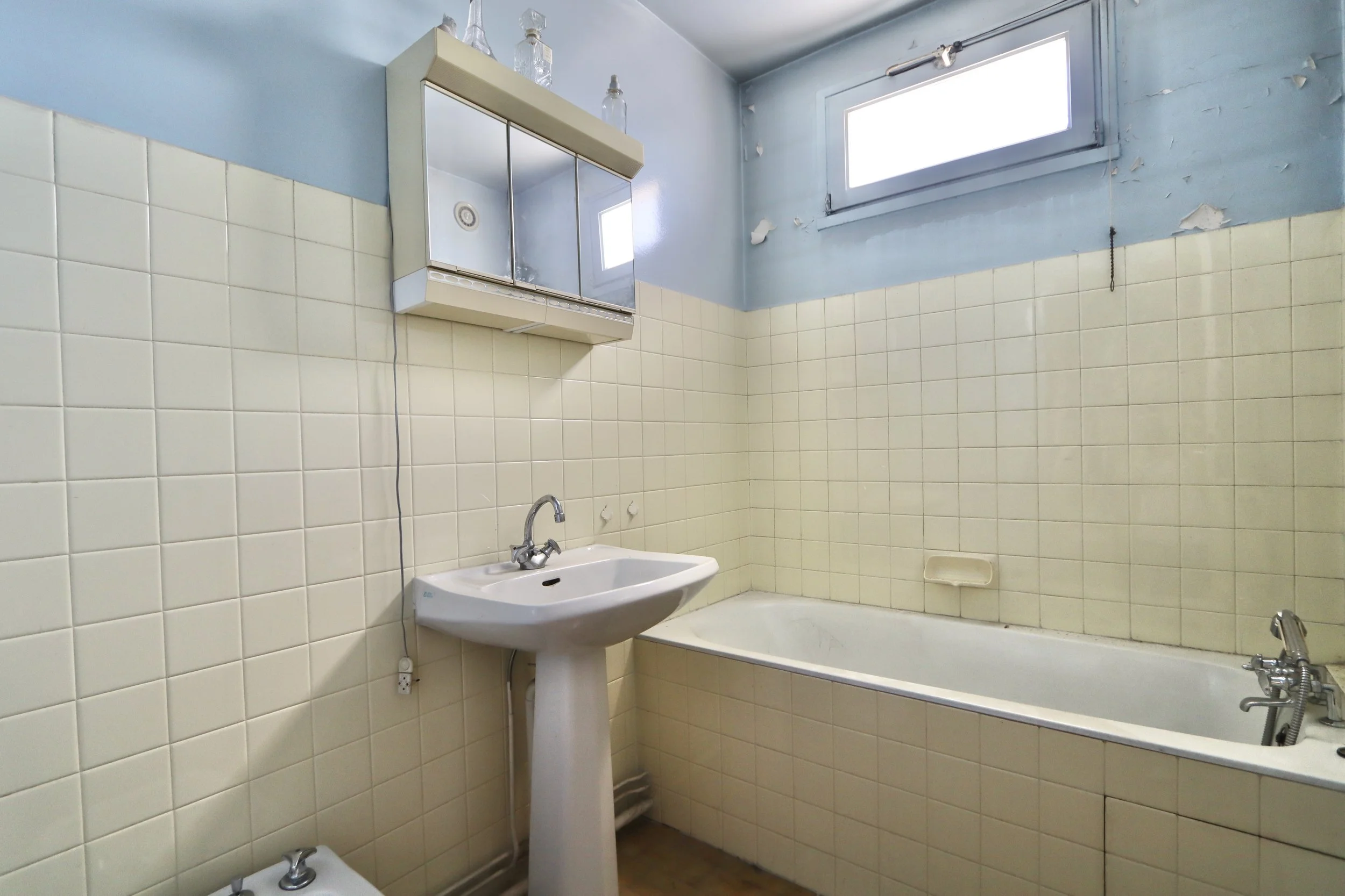 Avant : une salle de bain vieillissante, peu chaleureuse et fonctionnelle 