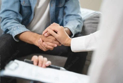 Zwei Menschen schütteln sich die Hand, während eine Person Notizen macht.