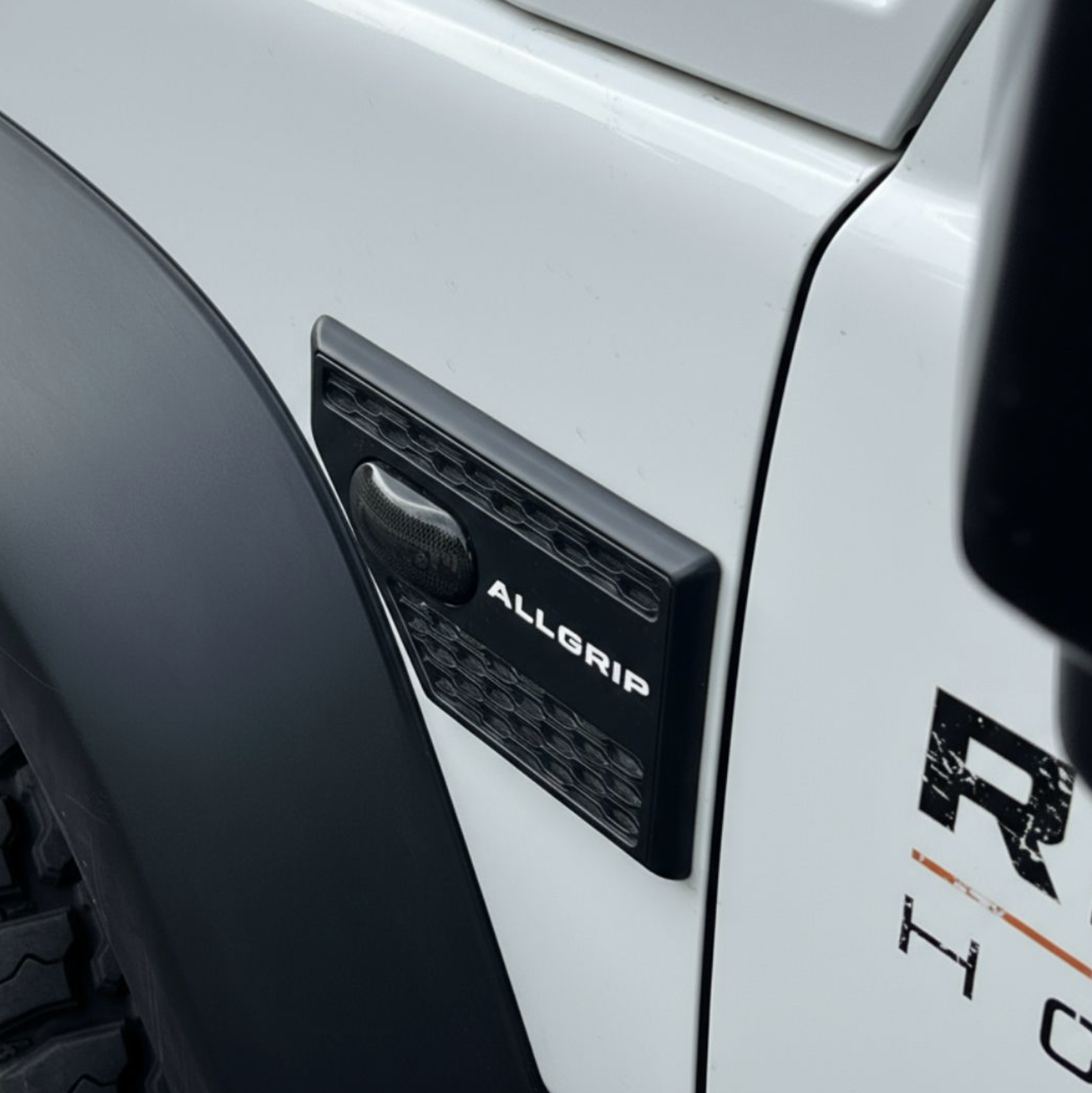 Close-up of a vehicle with a black Diablo logo and part of the word 'ALLGRIP' visible, next to a white box with partially visible text.