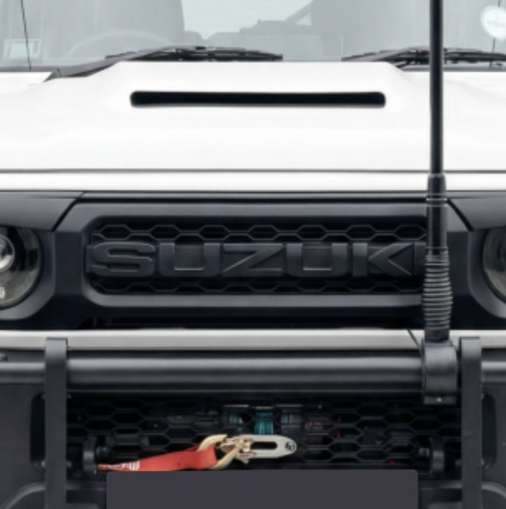 Front view of a Suzuki vehicle with exposed engine components, showing the radiator grille and engine bay.