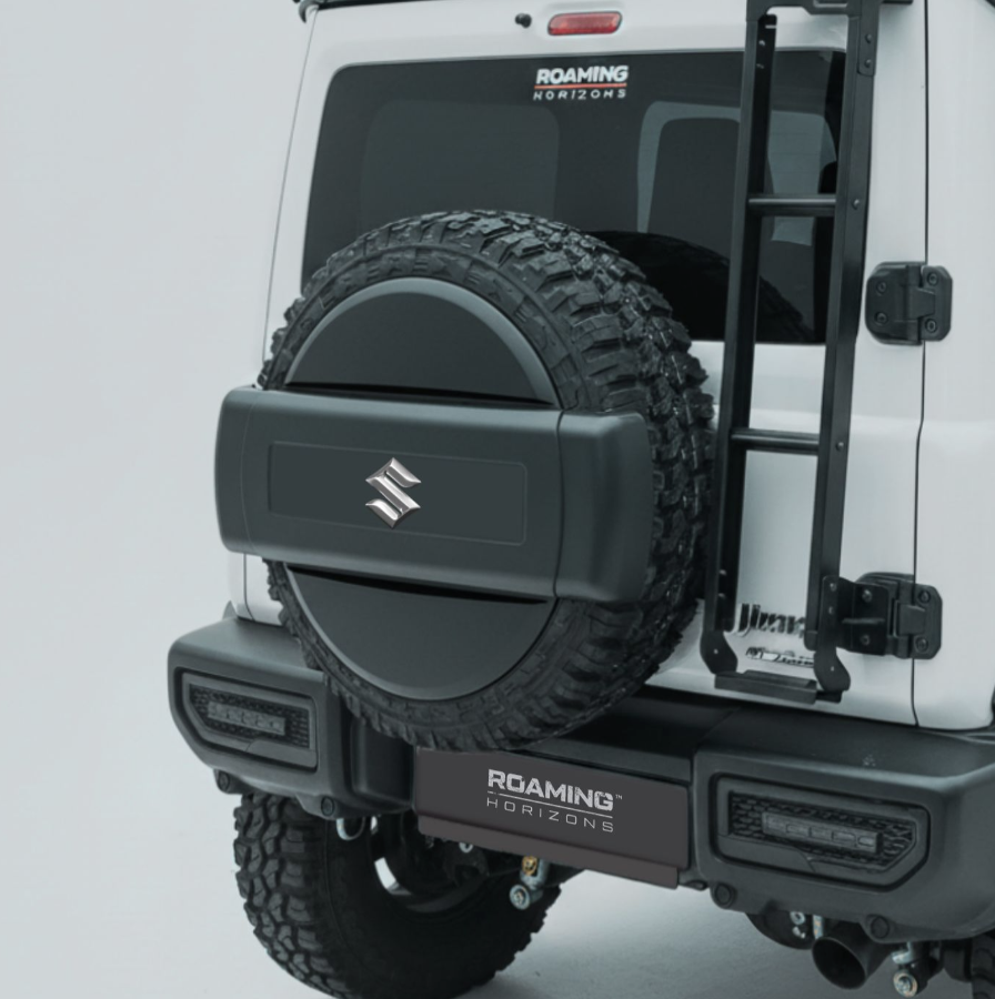 Rear view of a white Suzuki Jeep with off-road tires, a spare tire mounted on the back, and a Black Ladder on the right side. There are stickers that read 'Roaming Horizons' and 'Jeep'.