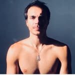 Portrait d'une personne non vêtue, cheveux courts, sans vêtements sur le haut du corps, fond gris