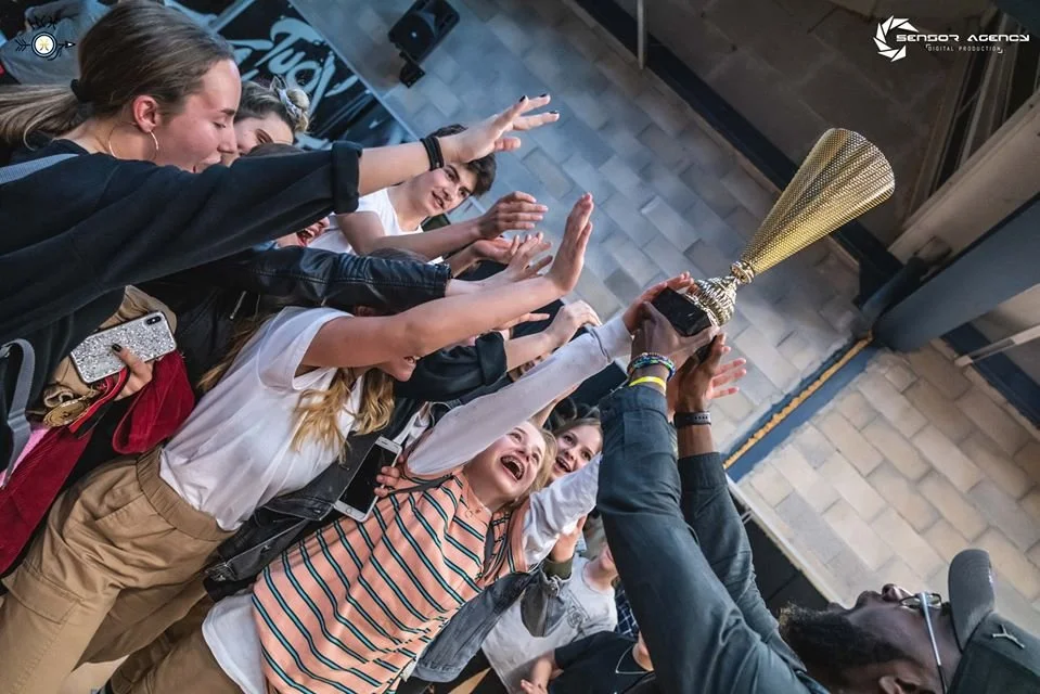 Un groupe de jeunes fillettes joyeuses tenant un trophée doré ensemble.