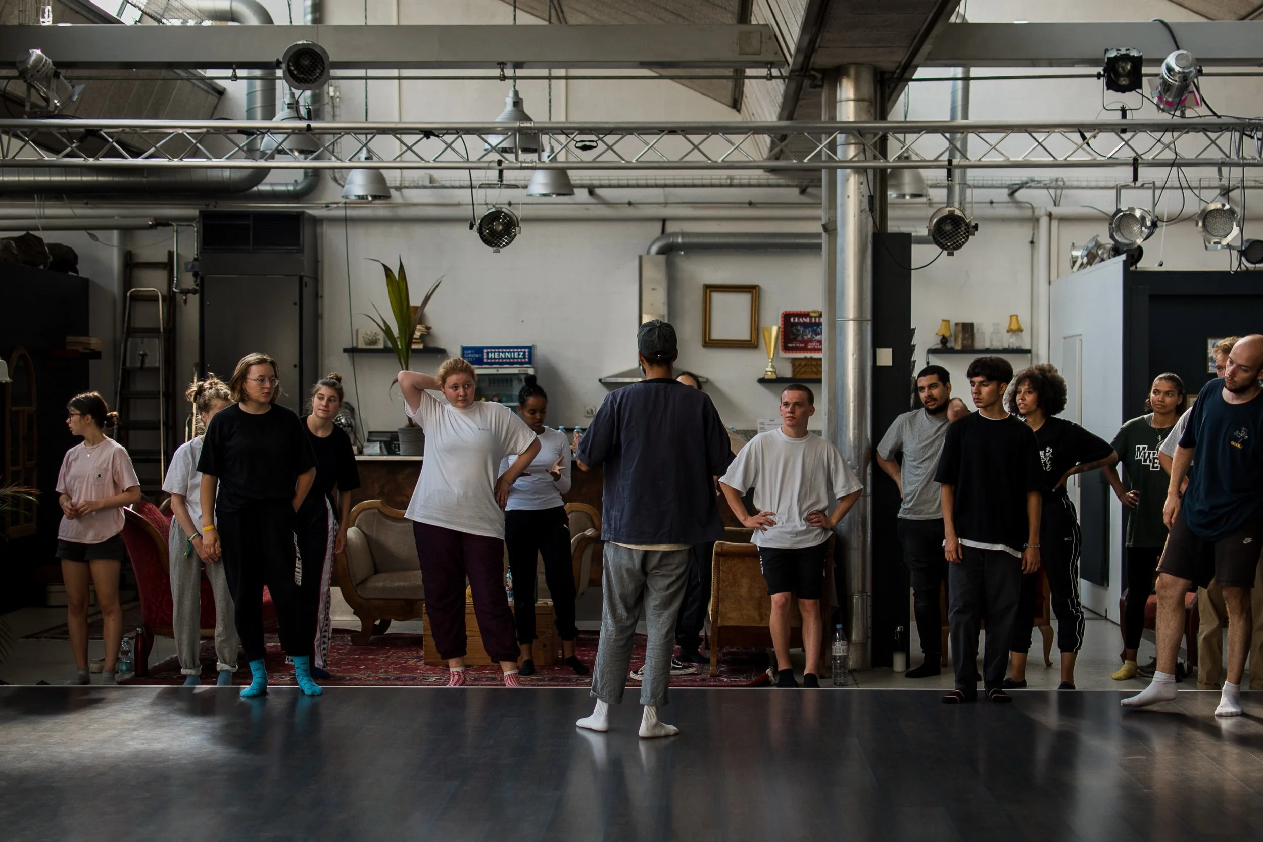 Groupe de personnes en train de pratiquer une activité de danse ou de théâtre dans une salle industrielle.