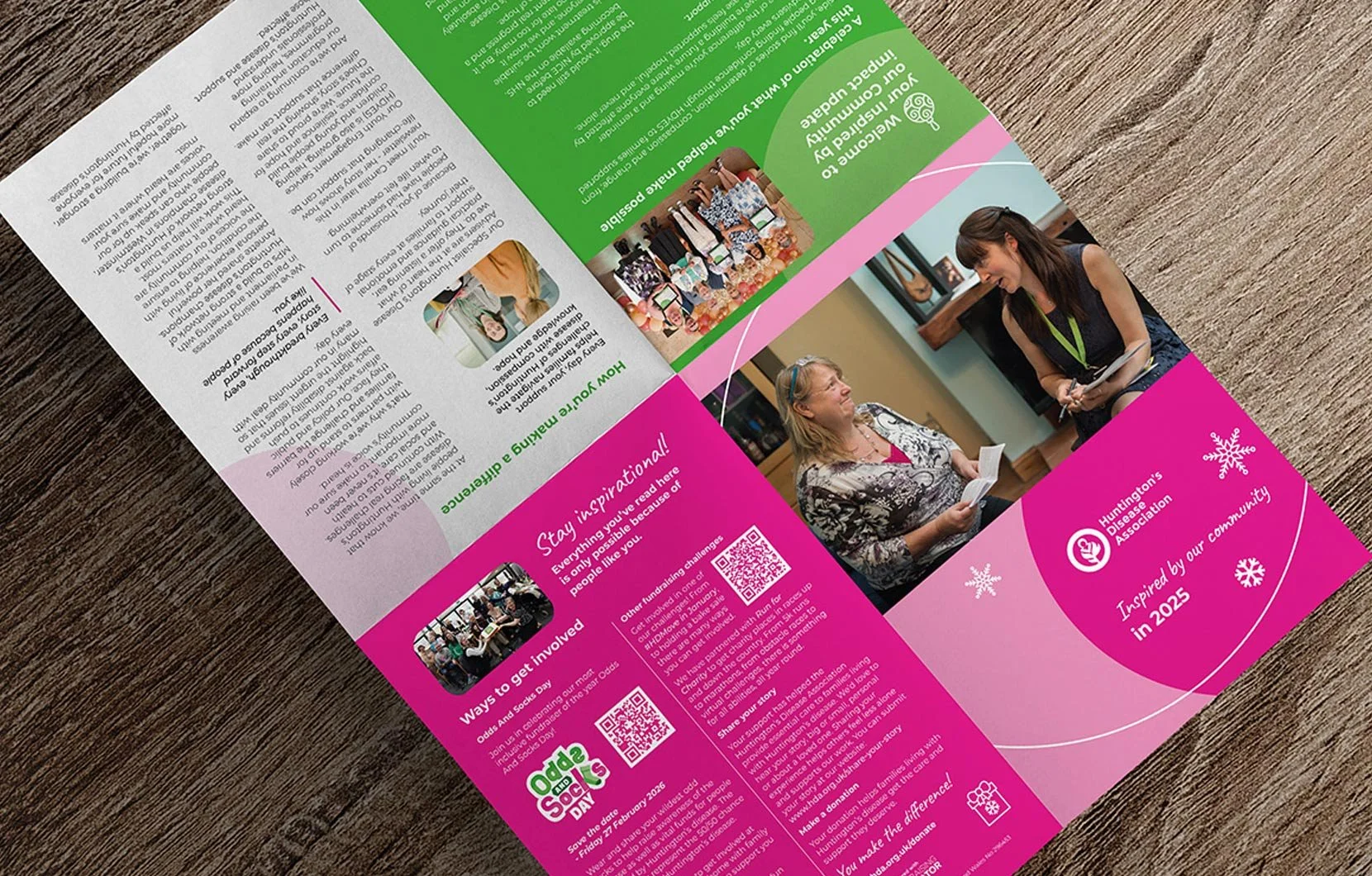 A folded brochure promoting a community event with images of women interacting, colorful sections with text, and snowflake illustrations, on a wooden surface.