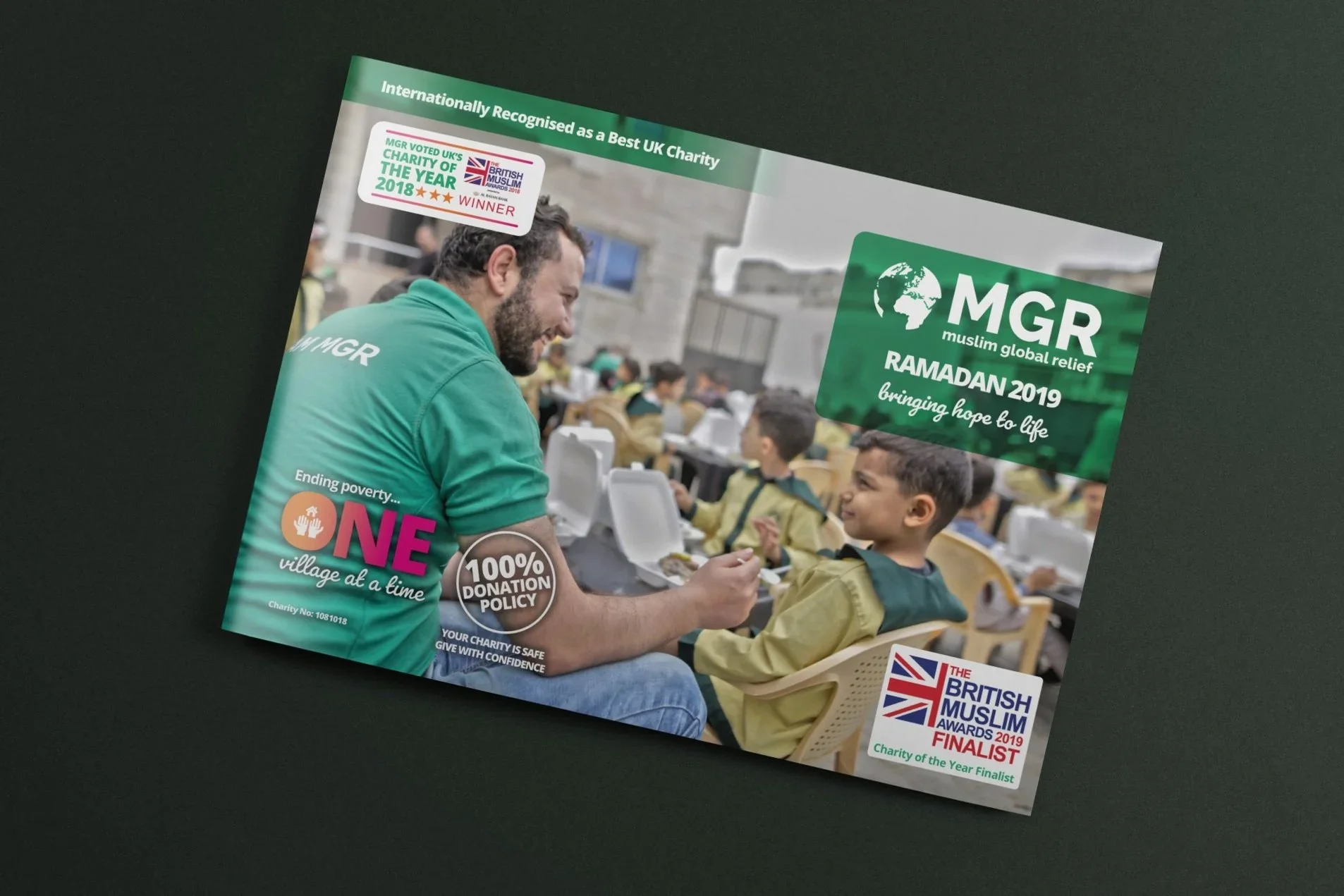 A man wearing a green T-shirt talking to children at an outdoor charity event, with text about Ramadan and the British Muslim Awards on the flyer.