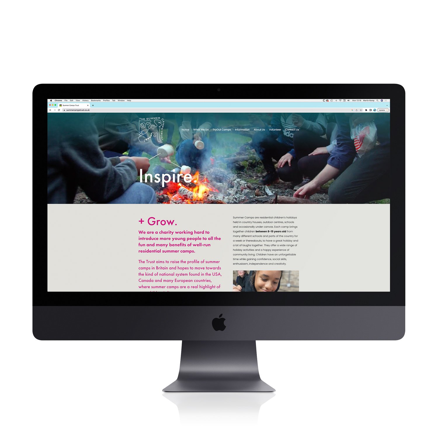 A website displayed on an Apple iMac screen showcasing summer camp information, including an image of children around a campfire.