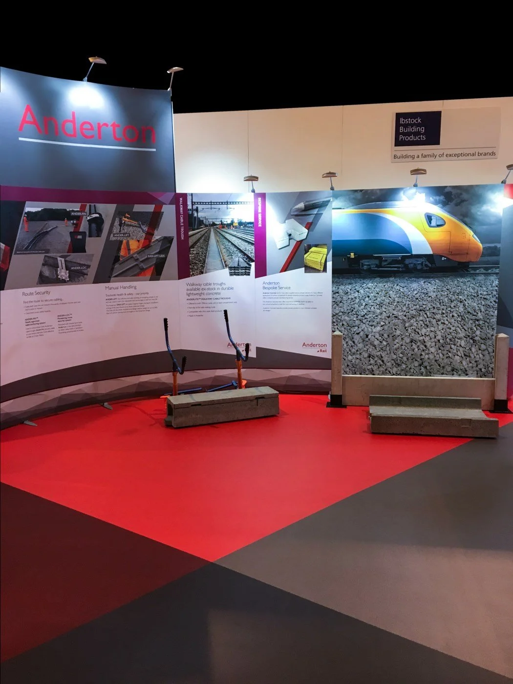 Exhibition booth displaying railroad track construction materials and train images with informational posters and a large graphic of a modern train.