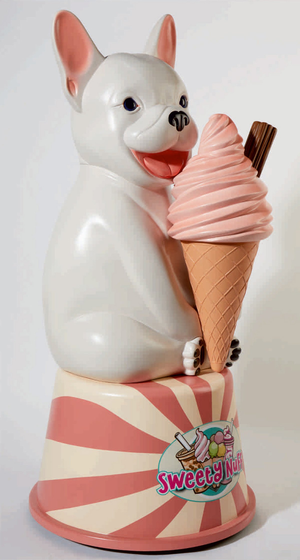 A decorative statue of a white French Bulldog holding a large pink soft-serve ice cream cone with a chocolate stick, sitting on a pink and white striped base with a "Sweety Nuff" ice cream logo.